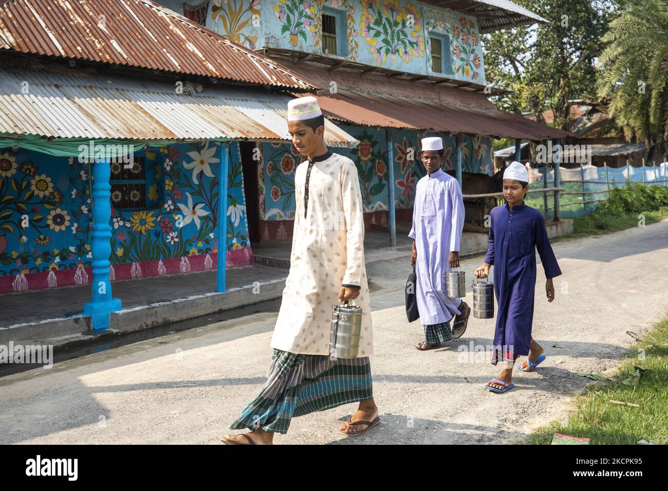 I residenti camminano attraverso la villa alpona al villaggio di Alpona in chapainawabganj il 8 ottobre 2021. La gente del posto dice che l'alpanacultura proviene dai villaggi remoti del più grande Rajshahi della famiglia indù. La maggior parte delle case qui sono fatte di argilla. Prima di varie feste di Tithi, ci furono tre gocce sulle pareti di fango di questa casa, e gli spuntini bianchi furono tirati giù. Ora non sono disegnati tre toni, dipinti fiori, uccelli, cieli, fiumi e le classiche immagini del Bengala. (Foto di Ahmed Salahuddin/NurPhoto) Foto Stock