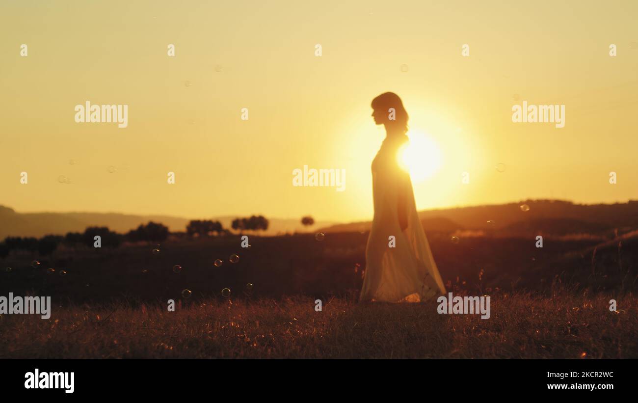 Ragazza cammina a piedi nudi in campagna al tramonto Foto Stock