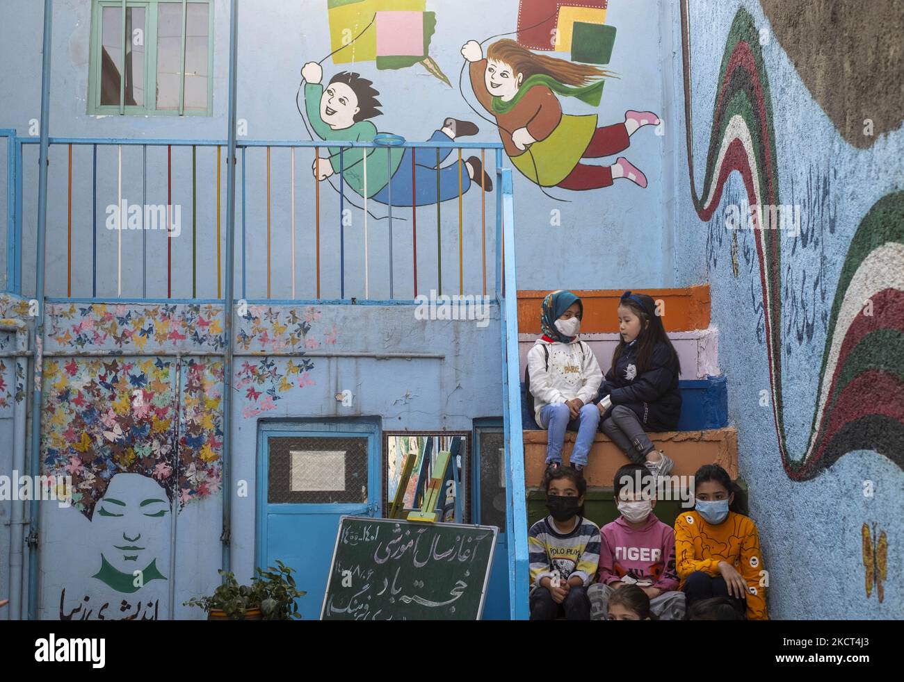 Gli scolari afghani rifugiati e le studentesse siedono sulle scale della scuola di Farhang nel primo giorno del nuovo anno accademico? Nel sud di Teheran il 1 novembre 2021. La scuola di Farhang è stata fondata nel 2000 dal rifugiato afgano Nader Mousavi che si è laureato in sociologia presso l'Università di Teheran, per i bambini rifugiati afghani, E ora due anni dopo l’inizio dell’epidemia COVID-19 in Iran, dove la scuola operava a tempo parziale, ha iniziato a funzionare a tempo pieno e le scolaresche e gli scolari afghani possono frequentare la scuola. Le famiglie non devono pagare i soldi per le tasse scolastiche come io Foto Stock