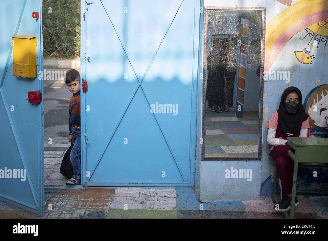 Un giovane rifugiato afghano guarda come sta alla porta della scuola di Farhang nel primo giorno del nuovo anno accademico? Nel sud di Teheran il 1 novembre 2021. La scuola di Farhang è stata fondata nel 2000 dal rifugiato afgano Nader Mousavi che si è laureato in sociologia presso l'Università di Teheran, per i bambini rifugiati afghani, E ora due anni dopo l’inizio dell’epidemia COVID-19 in Iran, dove la scuola operava a tempo parziale, ha iniziato a funzionare a tempo pieno e le scolaresche e gli scolari afghani possono frequentare la scuola. Le famiglie non devono pagare i soldi per il tuitio Foto Stock