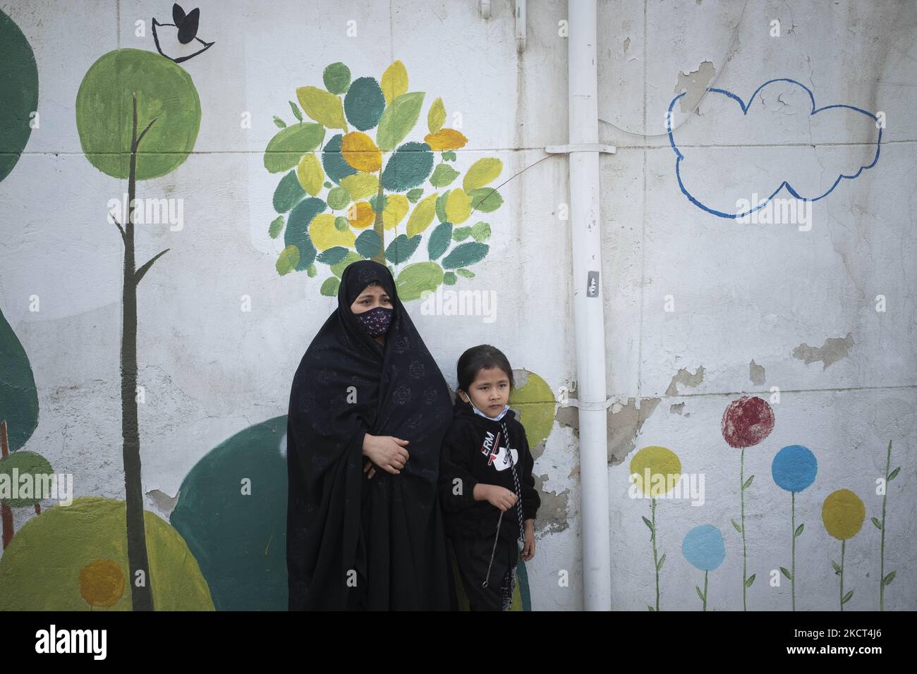 Una donna rifugiata afghana e la sua figlia si distinguono dalla scuola di Farhang nel primo giorno del nuovo anno accademico? Nel sud di Teheran il 1 novembre 2021. La scuola di Farhang è stata fondata nel 2000 dal rifugiato afgano Nader Mousavi che si è laureato in sociologia presso l'Università di Teheran, per i bambini rifugiati afghani, E ora due anni dopo l’inizio dell’epidemia COVID-19 in Iran, dove la scuola operava a tempo parziale, ha iniziato a funzionare a tempo pieno e le scolaresche e gli scolari afghani possono frequentare la scuola. Le famiglie non devono pagare i soldi per le tasse scolastiche come Foto Stock