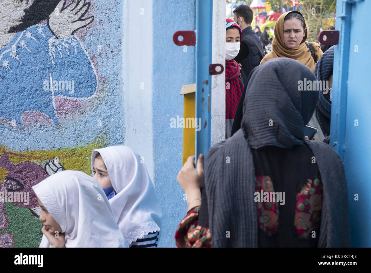 Un membro del personale della scuola afghana di Farhang parla con le madri di giovani studentesse rifugiate alle porte della scuola di Farhang nel primo giorno del nuovo anno accademico? Nel sud di Teheran il 1 novembre 2021. La scuola di Farhang è stata fondata nel 2000 dal rifugiato afgano Nader Mousavi che si è laureato in sociologia presso l'Università di Teheran, per i bambini rifugiati afghani, E ora due anni dopo l’inizio dell’epidemia COVID-19 in Iran, dove la scuola operava a tempo parziale, ha iniziato a funzionare a tempo pieno e le scolaresche e gli scolari afghani possono frequentare la scuola. Le famiglie fanno ha Foto Stock