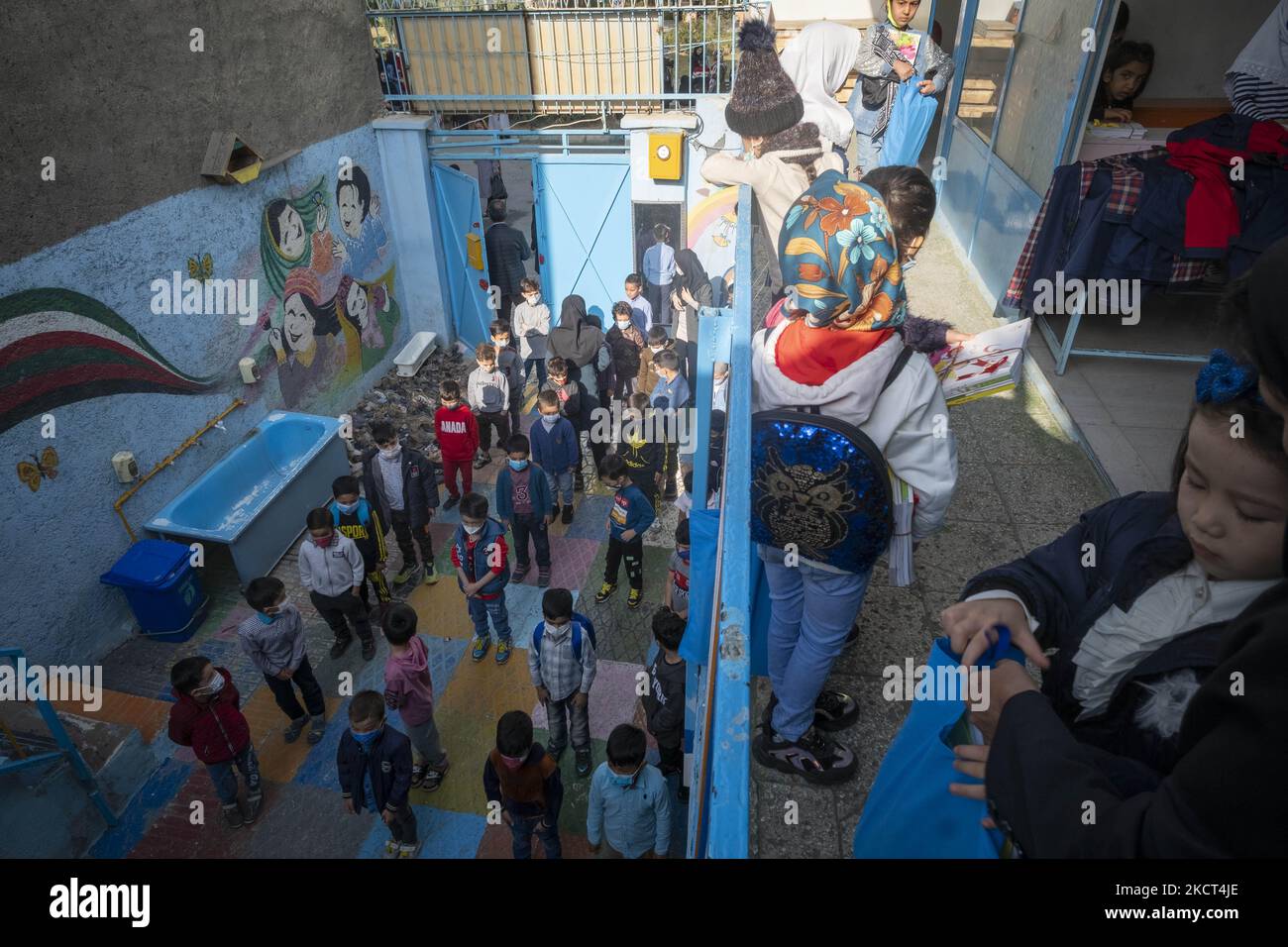 Gli scolari afghani rifugiati si allineano mentre aspettano di ricevere i libri scolastici alla scuola di Farhang nel primo giorno del nuovo anno accademico? Nel sud di Teheran il 1 novembre 2021. La scuola di Farhang è stata fondata nel 2000 dal rifugiato afgano Nader Mousavi che si è laureato in sociologia presso l'Università di Teheran, per i bambini rifugiati afghani, E ora due anni dopo l’inizio dell’epidemia COVID-19 in Iran, dove la scuola operava a tempo parziale, ha iniziato a funzionare a tempo pieno e le scolaresche e gli scolari afghani possono frequentare la scuola. Le famiglie non devono pagare i soldi per la t Foto Stock