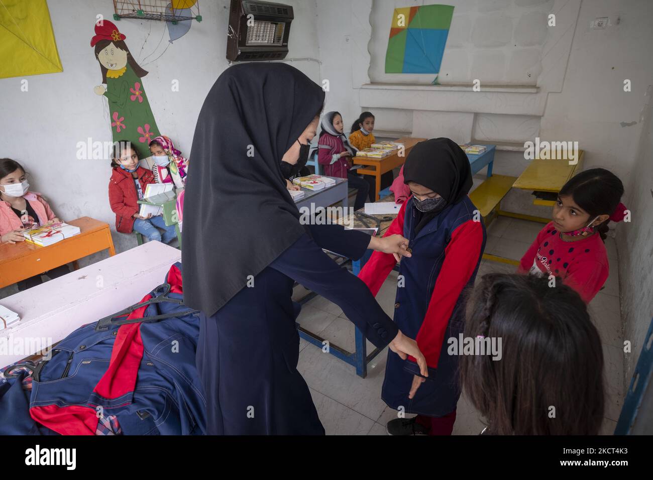 Insegnante afghana, Mahboobeh Mohammadi-32 Chi è nato in Iran, verifica le dimensioni di una divisa scolastica per una studentessa afghana rifugiata in un'aula alla scuola di Farhang nel primo giorno del nuovo anno accademico? Nel sud di Teheran il 1 novembre 2021. La scuola di Farhang è stata fondata nel 2000 dal rifugiato afgano Nader Mousavi che si è laureato in sociologia presso l'Università di Teheran, per i bambini rifugiati afghani, E ora, due anni dopo l'inizio dell'epidemia COVID-19 in Iran, dove la scuola operava a tempo parziale, ha iniziato ad operare scolaresche a tempo pieno e afghane Foto Stock