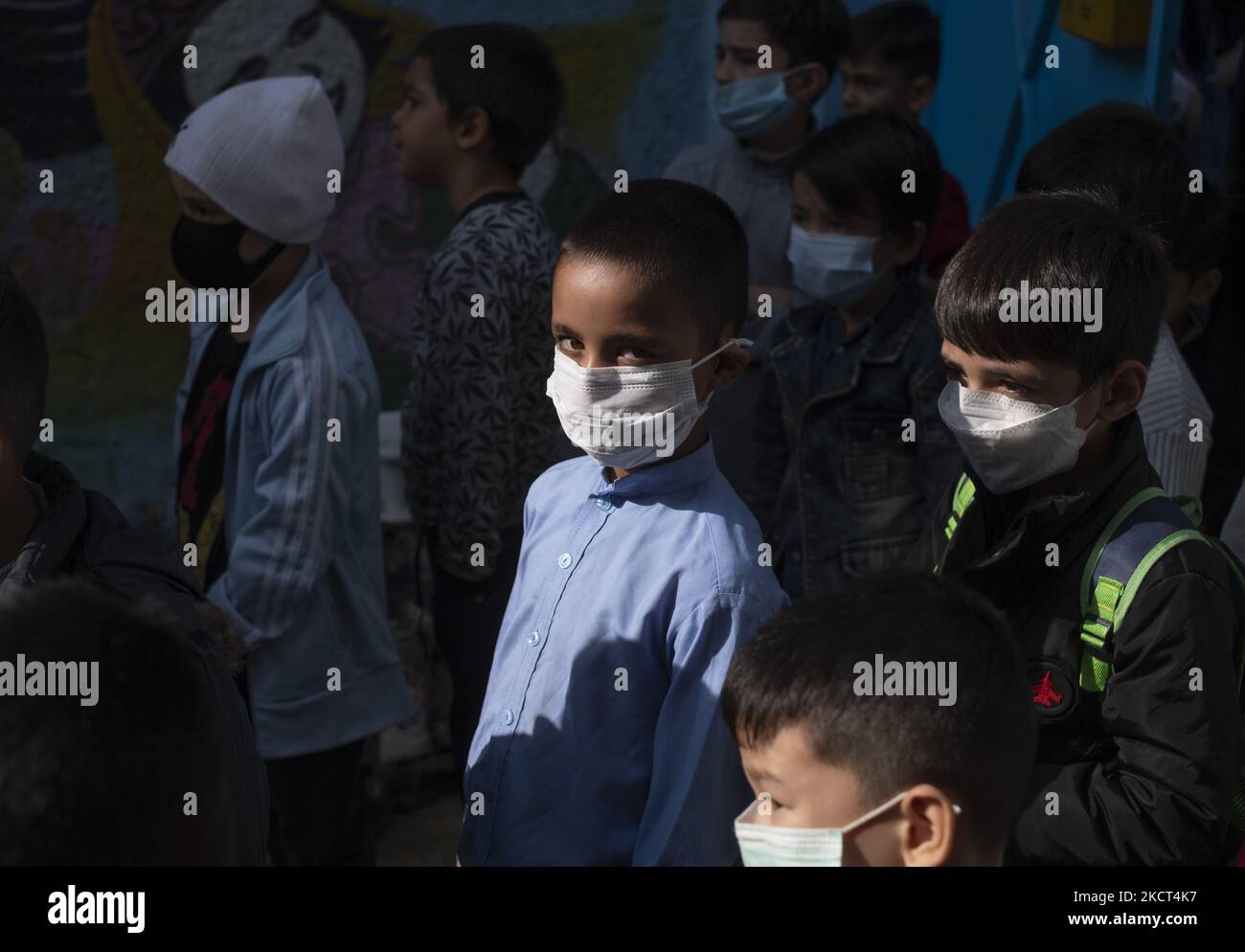 Un allieva afghano rifugiato che indossa una maschera protettiva guarda come si trova alla scuola di Farhang nel primo giorno del nuovo anno accademico? Nel sud di Teheran il 1 novembre 2021. La scuola di Farhang è stata fondata nel 2000 dal rifugiato afgano Nader Mousavi che si è laureato in sociologia presso l'Università di Teheran, per i bambini rifugiati afghani, E ora due anni dopo l’inizio dell’epidemia COVID-19 in Iran, dove la scuola operava a tempo parziale, ha iniziato a funzionare a tempo pieno e le scolaresche e gli scolari afghani possono frequentare la scuola. Le famiglie non devono pagare m Foto Stock