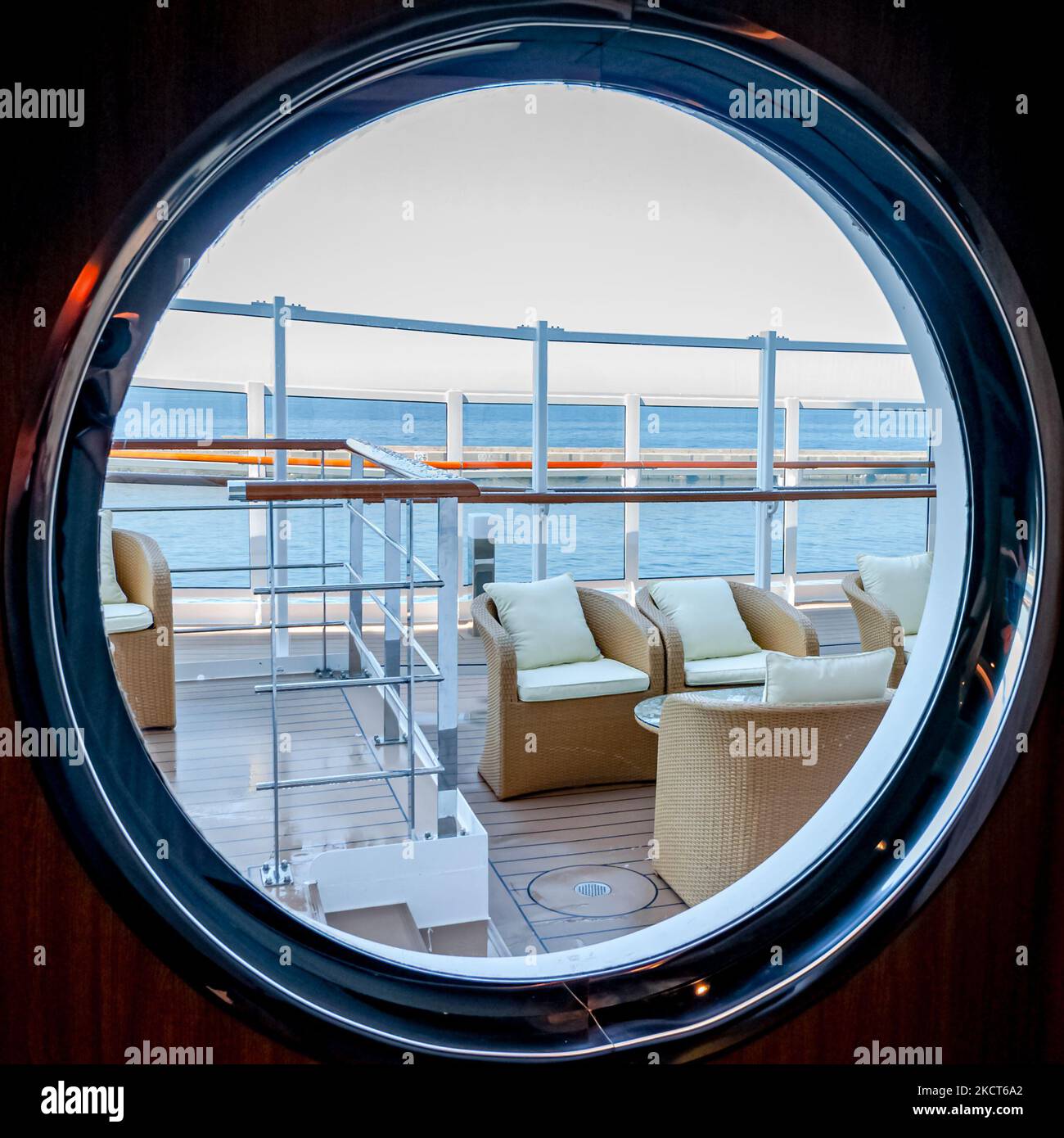 Vista di una lounge all'aperto sul ponte sul lungomare di una nave da crociera attraverso un oblò. Foto Stock