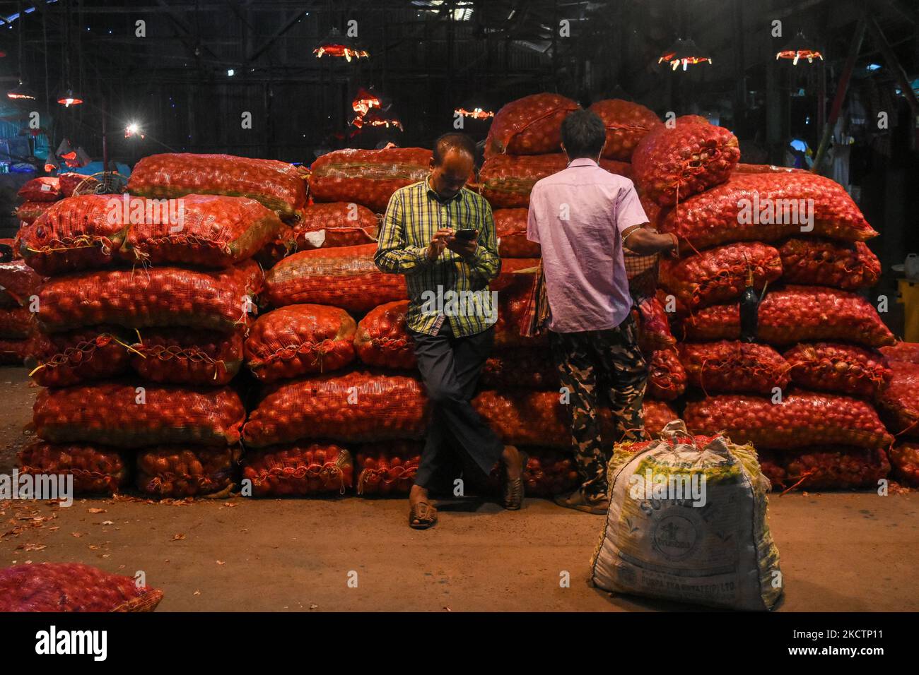 La gente è vista davanti ai sacchetti delle cipolle , all'interno di un mercato agricolo a Kolkata , India , il 12 novembre 2021. Il PIL indiano è previsto aumentare a $406 miliardi di dollari entro il 2050 mentre la più grande economia asiatica del 3rd balza verso l'obiettivo zero netto , Secondo Observer Research Foundation. L' economia indiana è cresciuta del 8,3% rispetto al Q2 dell' anno fiscale in corso , a causa dell' aumento delle vaccinazioni , della spesa pubblica e del miglioramento dei consumi . (Foto di Debarchan Chatterjee/NurPhoto) Foto Stock
