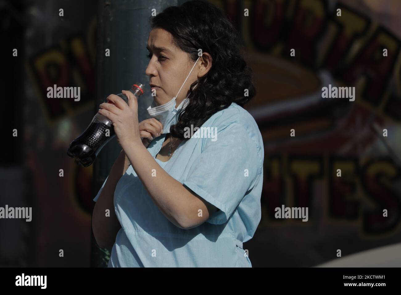 Un'infermiera beve una bibita mentre attraversa la strada su Taxqueña Avenue e Tláhuac, Città del Messico, vicino a un mercato e un minimarket durante le vendite delle pinne di Buen durante l'emergenza sanitaria COVID-19 e il semaforo verde epidemiologico nella capitale. (Foto di Gerardo Vieyra/NurPhoto) Foto Stock