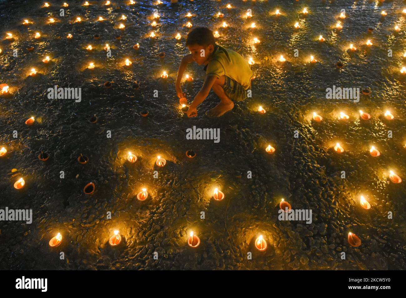 Un bambino piccolo è visto illuminare lampade ad olio ad un ghat del fiume in occasione di Dev Deepavali a Kolkata , India , il 19 novembre 2021 .Dev Deepavali è un festival indù che si celebra a Karthik Purnima , 15 giorni dopo Diwali e si ritiene che sia Diwali degli dei . Devoti lampada ad olio leggero sui lati del fiume Ganges per rendere onore al fiume e alla sua Dea residente. (Foto di Debarchan Chatterjee/NurPhoto) Foto Stock