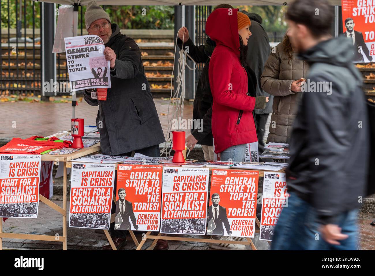 Città di Westminster, Londra, Regno Unito. 5th Nov 2022. Il tempo a Londra è stato coperto e piovoso. I visitatori sono ancora fuori a vedere le attrazioni. Sono in corso i preparativi per una protesta contro il governo. La persona che passa un tavolo socialista che fa pubblicità alle elezioni generali ora protesta e promuove uno sciopero generale Foto Stock