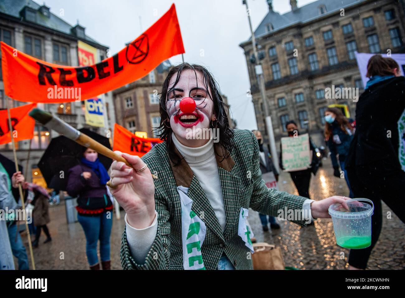 Un clown che rappresenta le pratiche di lavaggio del verde condotte dai marchi della moda, finge di dipingere con vernice verde, durante una sfilata di moda beffa Fast organizzata da XR, contro il Black Friday ad Amsterdam, il 27th novembre 2021. (Foto di Romy Arroyo Fernandez/NurPhoto) Foto Stock