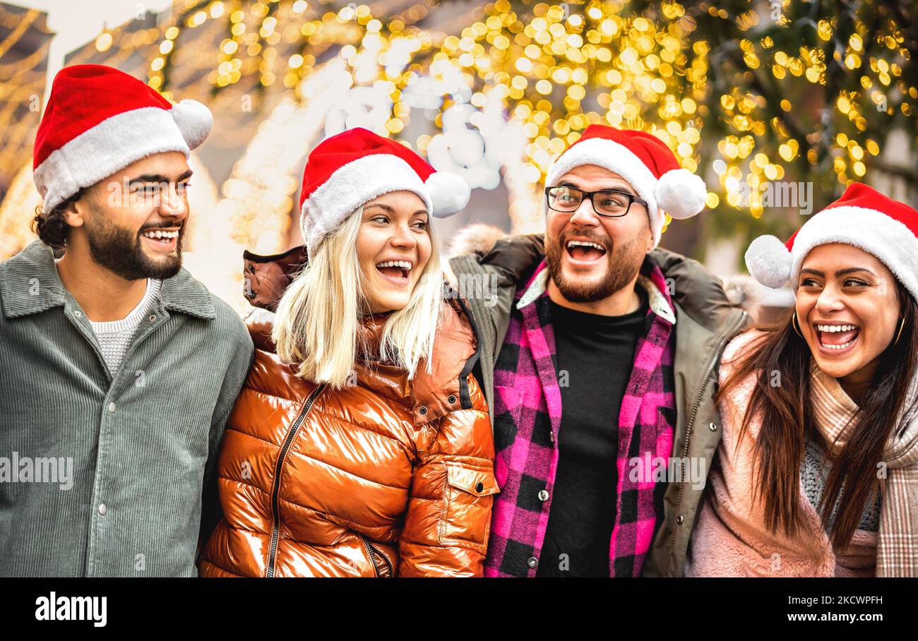 Felice gruppo di amici a piedi in città sotto decorazioni albero di Natale - concetto di stile di vita invernale con i giovani che indossano cappelli di babbo natale rosso avere Foto Stock