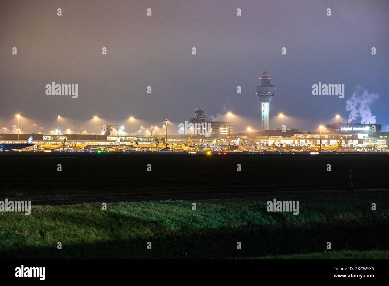 Vista notturna dell'aeroporto Schiphol di Amsterdam AMS con aereo alle porte. 14 casi della nuova variante COVID-19 Omicron sono stati confermati nei Paesi Bassi da passeggeri arrivati nella città olandese dal Sudafrica. Più di 600 passeggeri sono stati testati dai 2 voli con 61 confermati positivi per Covid-19. La polizia olandese ha arrestato in precedenza due passeggeri che si trovano in un hotel di quarantena mentre cercavano di fuggire. Molti paesi hanno sospeso i voli per il Sudafrica in un periodo già difficile con la pandemia di coronavirus che ha avuto un impatto negativo sul business dell'aviazione. Foto Stock