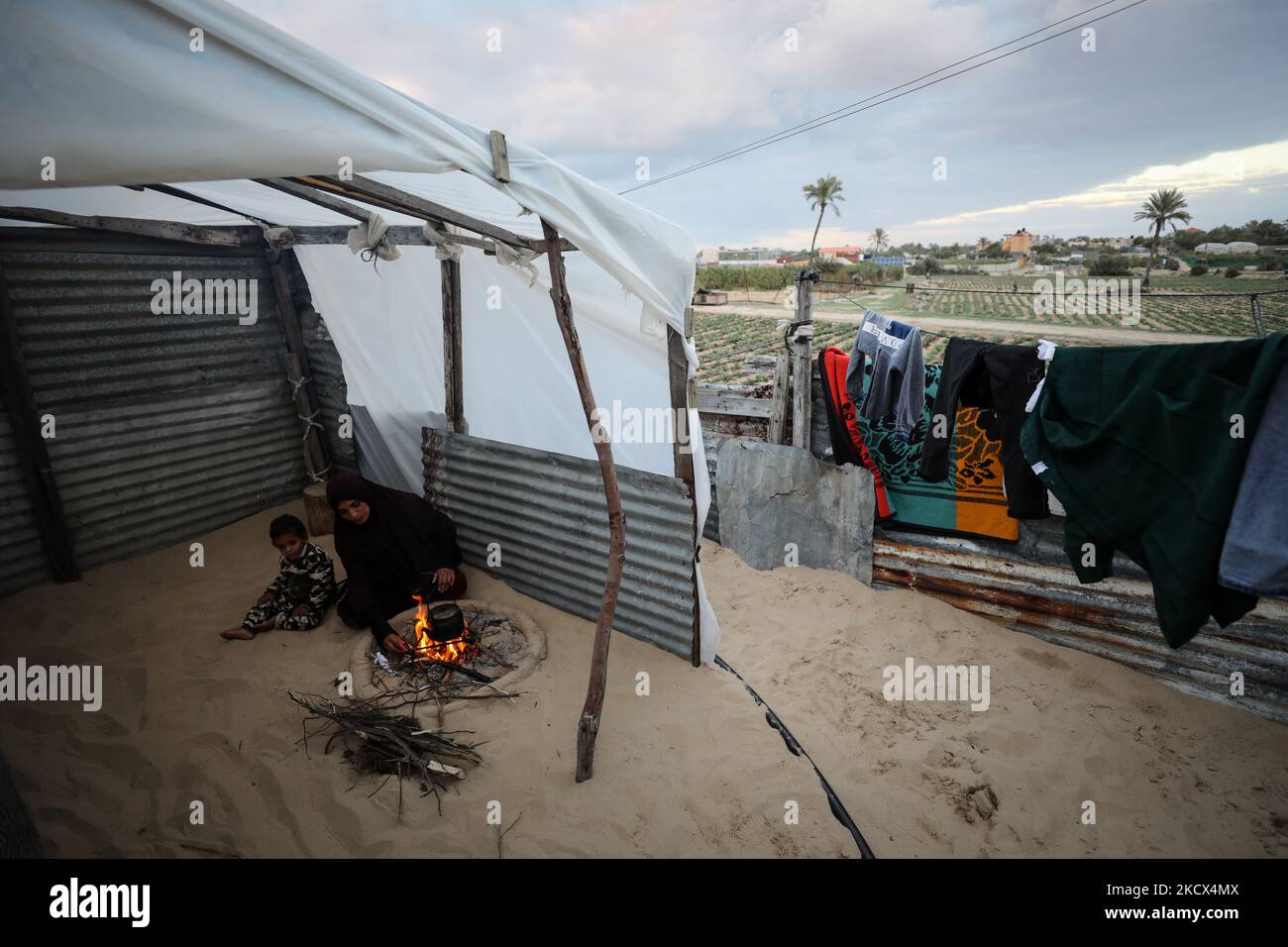 I palestinesi siedono intorno ad un incendio sotto la copertura di una tenda in un quartiere povero di Khan Younis nella striscia di Gaza meridionale, giovedì 2 dicembre 2021. (Foto di Majdi Fathi/NurPhoto) Foto Stock