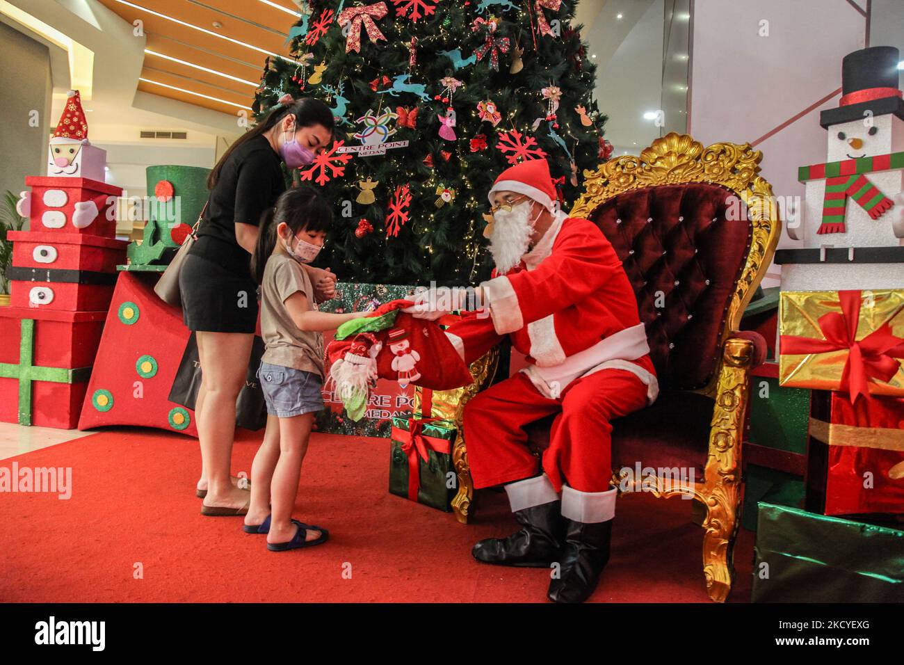 Un uomo che indossa il costume di Babbo Natale si siede per aspettare i clienti alle caramelle di?gives ai bambini al centro commerciale di Centre Point durante i festeggiamenti di Natale il 26 dicembre 2021 a Medan, Indonesia. Natale è una festa nazionale in Indonesia, anche se solo circa il dieci per cento della popolazione è cristiana., dove adoratori frequentano la massa con rigorosi protocolli sanitari in mezzo a crescenti casi della variante COVID-19, Omicron. (Foto di Ivan Damanik/NurPhoto) Foto Stock