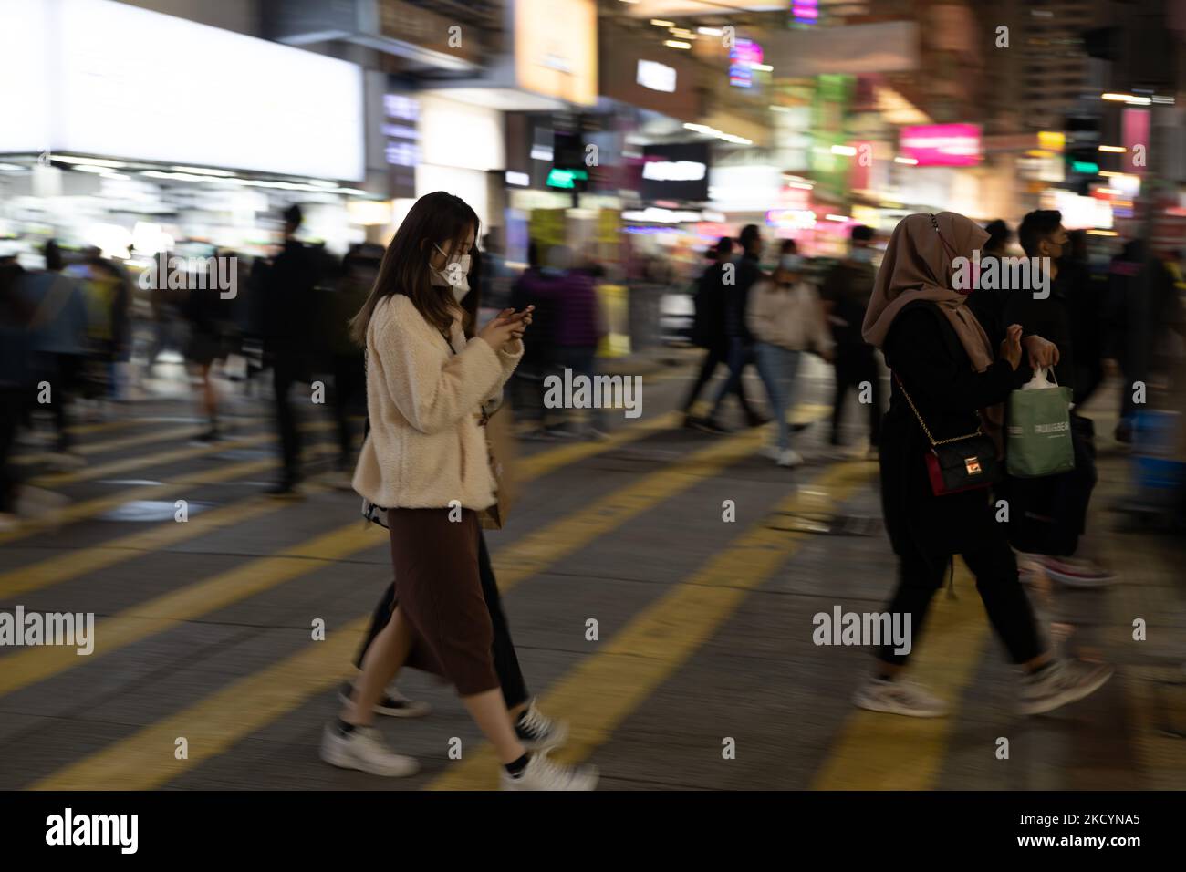 Le persone che indossano le maschere attraversano una strada a Mongkok, a Hong Kong, Cina, 2 gennaio 2022. (Foto di Marc Fernandes/NurPhoto) Foto Stock