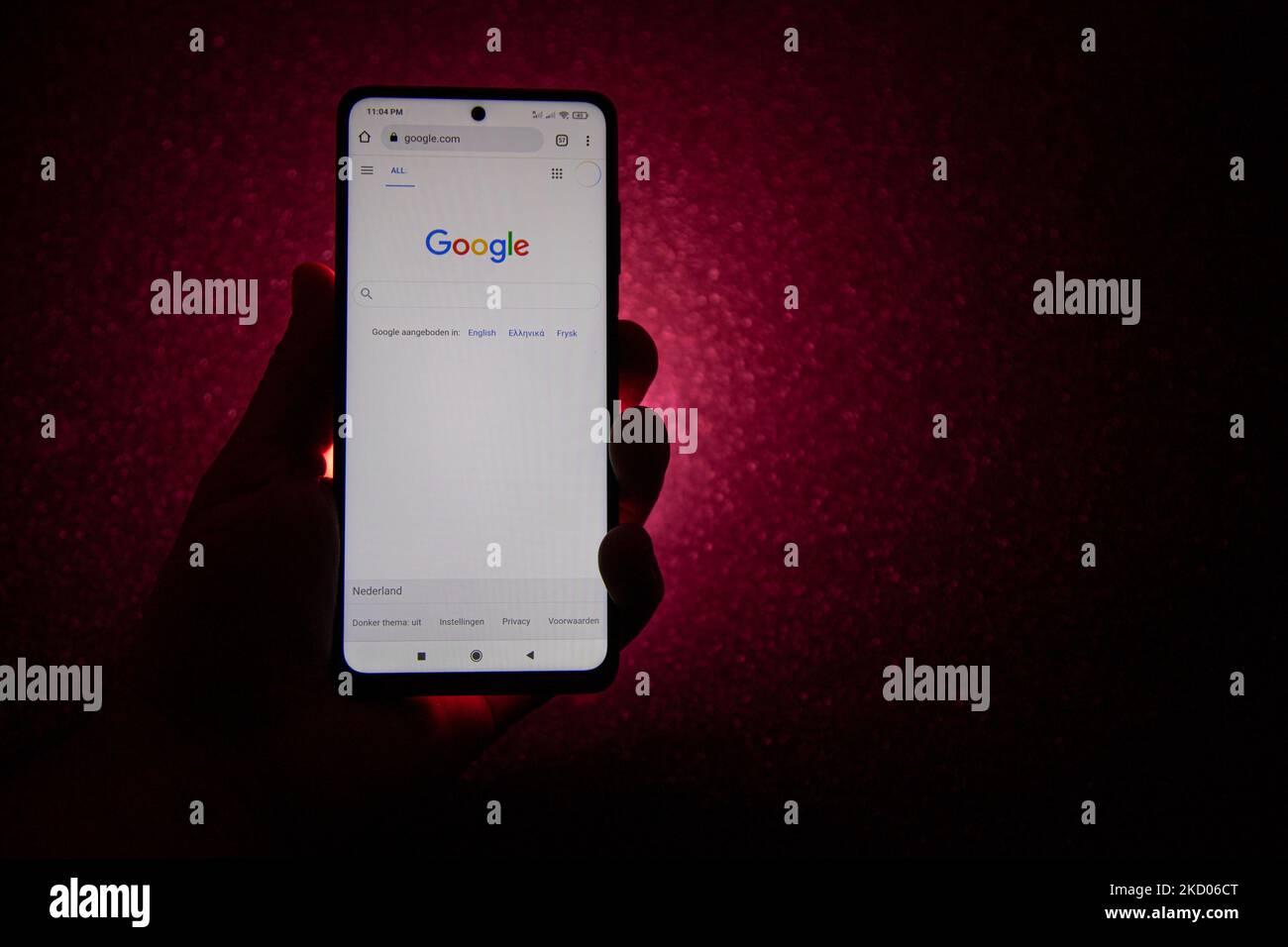 Logo Google su uno smartphone tenuto da una mano con sfondo rosso scuro. Logo Google closeup visualizzato su uno schermo del telefono, smartphone il logo o il motore di ricerca in vari sfondi come la tastiera, la texture illuminata scura o uno schermo del computer, come si vede in questa illustrazione di esposizione multipla, il simbolo dell'azienda è riconosciuto a livello globale. Google, LLC è un colosso tecnologico americano, una multinazionale che si specializza nei servizi e nei prodotti connessi a Internet, che includono le tecnologie di pubblicità online, un motore di ricerca, il cloud computing, il software e l'hardware. È considerato o Foto Stock