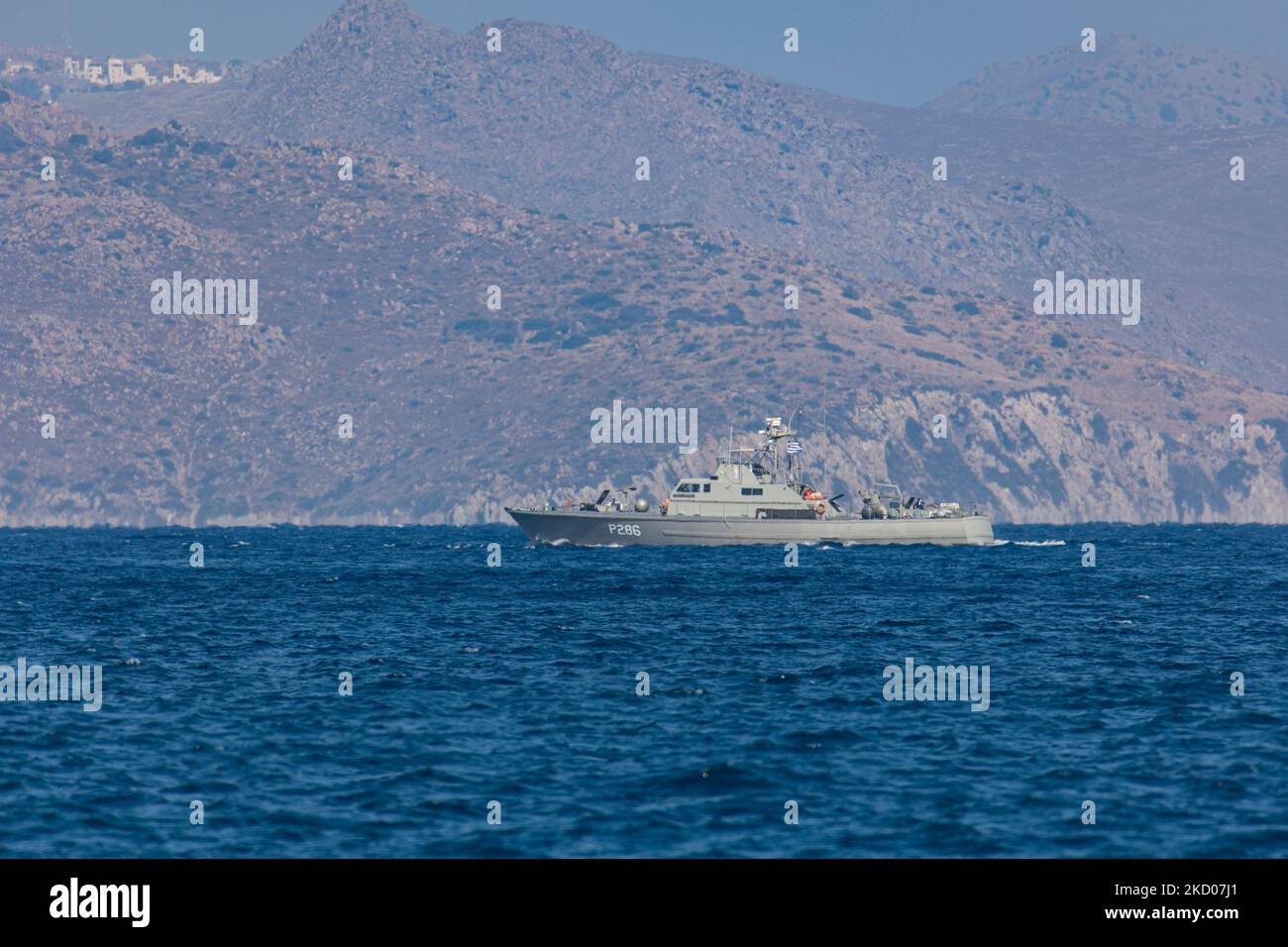 Una nave di pattuglia greca della Marina ellenica sta pattugliando i confini dell'acqua del Mar Egeo tra la Grecia e la Turchia, appena fuori dall'isola di Kos con la Turchia sullo sfondo con case estive, resort e alberghi visibili. I pattugliamenti sono destinati a scopi militari, ma anche a imbarcazioni con rifugiati e migranti, oltre alla forza FRONTEX che protegge i confini europei dalla crisi dei rifugiati. La nave che pattuglia i richiedenti asilo che cercano di attraversare con un gommone della costa turca è una piccola nave missilistica di classe Diopos Antoniou P286 Hellenic Navys Kelefstis Stamou. L'isola di Kos e la costa turca fr Foto Stock