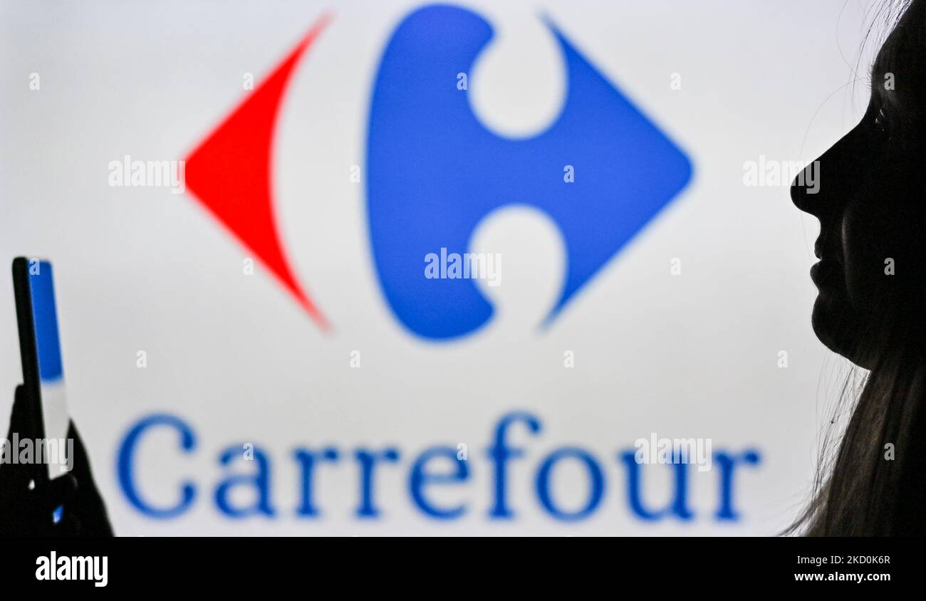 Immagine di una donna che tiene un telefono cellulare davanti al logo Carrefour visualizzato sullo schermo di un computer. Martedì 12 gennaio 2021, a Edmonton, Alberta, Canada. (Foto di Artur Widak/NurPhoto) Foto Stock