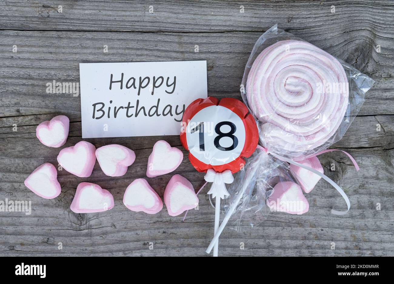 Buon 18th biglietto di auguri di compleanno e marshmallows rosa giacciono su un asse di legno Foto Stock
