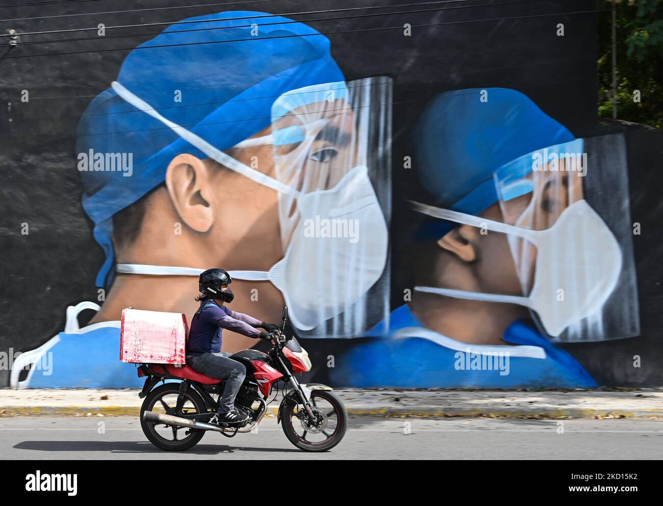 Un motociclista guida oltre un murale di medici che indossano maschere facciali dipinte nel centro di Merida dagli artisti messicani Mare - Nookie. Domenica 23 gennaio 2022, a Merida, Yucatan, Messico. (Foto di Artur Widak/NurPhoto) Foto Stock