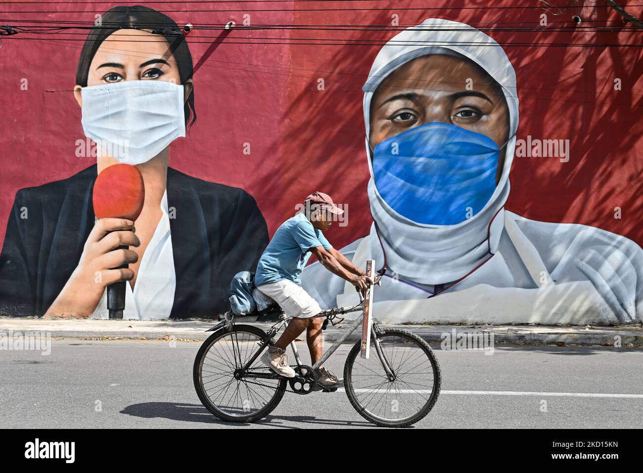 Un ciclista passato un murale di operai essenziali che indossano maschere facciali dipinte nel centro di Merida dagli artisti messicani Mare - Nookie. Domenica 23 gennaio 2022, a Merida, Yucatan, Messico. (Foto di Artur Widak/NurPhoto) Foto Stock