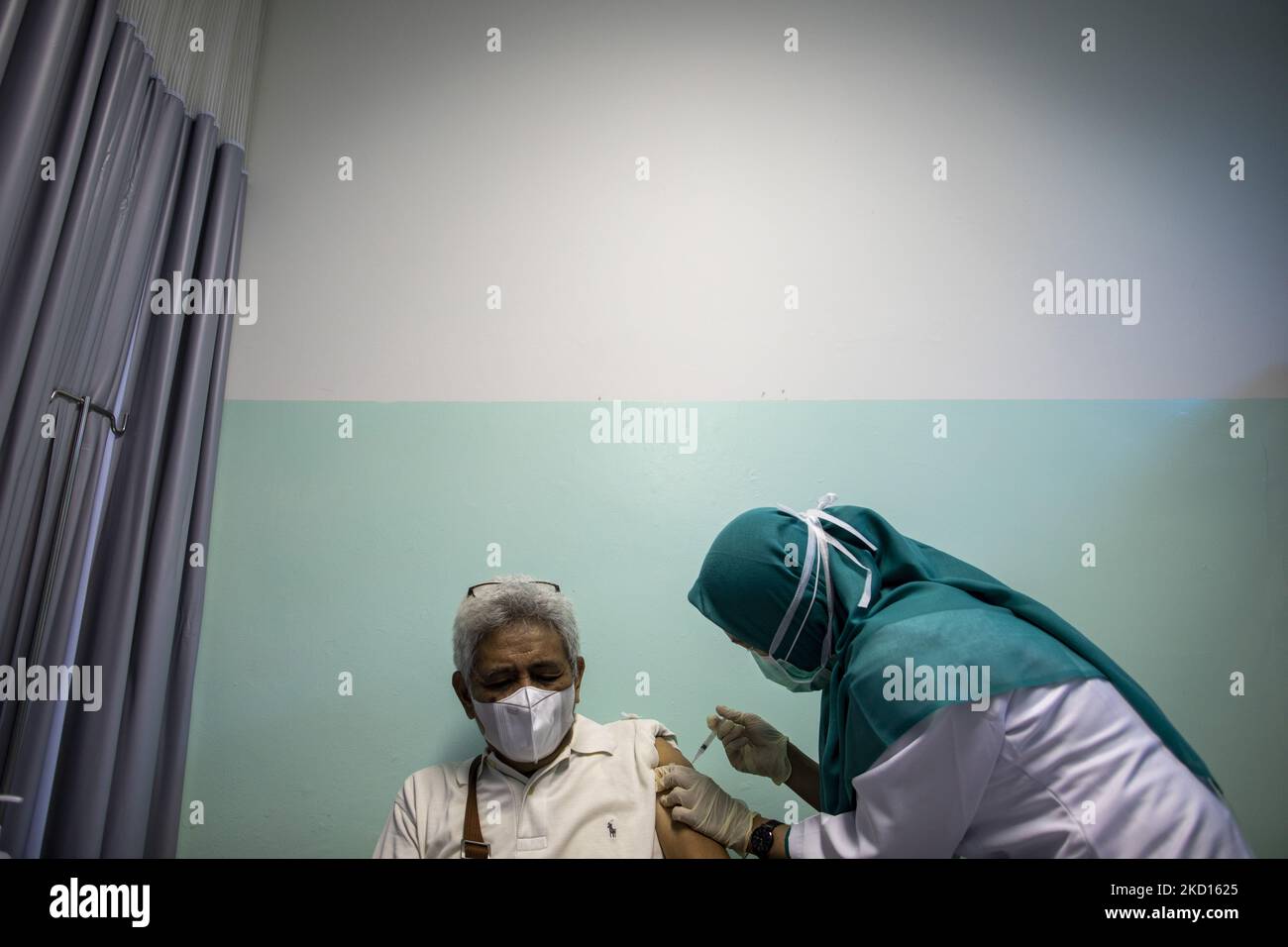 Un uomo chiude gli occhi mentre riceve un'iniezione di richiamo per il vaccino COVID-19. Implementazione del vaccino Covid-19 Booster per gli anziani presso il South Tangerang Hospital. Il governo continua a perseguire Booster, soprattutto per gli anziani, per prevenire i casi di morte a causa dell'aumento della variante di Omicron in Indonesia. (Foto di Donal Husni/NurPhoto) Foto Stock