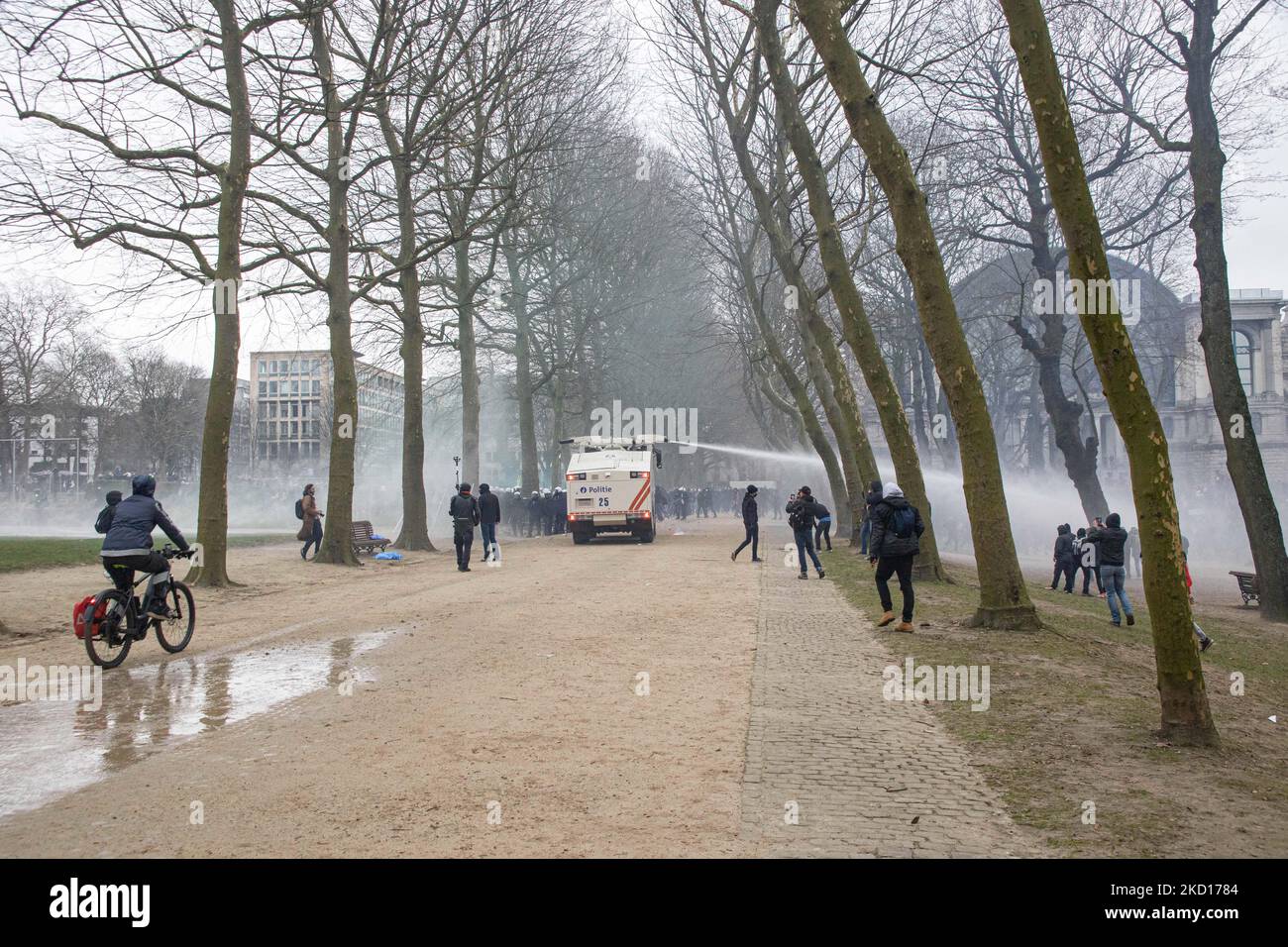 Il fuoco della polizia distruggerà il gas contro i manifestanti violenti e li spruzzerà con il cannone ad acqua del veicolo speciale. Migliaia di persone protestano durante la dimostrazione europea per la democrazia contro le misure correlate a Covid come il pass sanitario COVID e le restrizioni. I disordini hanno cominciato a scoppiare e la polizia spara gas lacrimogeni e cannone d'acqua mentre la protesta si è trasformata in violenta. La gente partecipa a una manifestazione contro le misure sanitarie a Bruxelles come il COVID Health Pass, il codice QR, le maschere facciali e la vaccinazione obbligatoria, usando come slogan principale e sulle bandiere il termine liberte tradotto come libertà. Autore Foto Stock