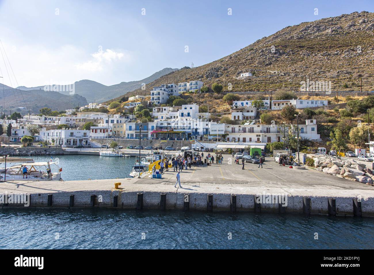 Scena del porto dell'isola con alcune piccole barche ormeggiate. Livadia, il porto e il villaggio principale dell'isola di Tilos con le case di architettura tradizionale imbiancate e la spiaggia con le acque cristalline del mare. Telos è una piccola isola greca mediterranea nel Mar Egeo, parte delle isole Dodecanesi, con una popolazione di 780 abitanti vicino alla costa turca. Alla fine del 2018 Tilos è diventata la prima isola del Mediterraneo a funzionare esclusivamente con energia eolica e solare, un'isola verde autosufficiente, un'iniziativa finanziata dall'UE per l'energia verde da fonti rinnovabili che proteggono il natu Foto Stock
