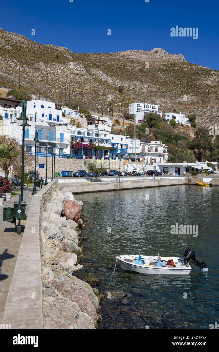 Scena del porto dell'isola con alcune piccole barche ormeggiate. Livadia, il porto e il villaggio principale dell'isola di Tilos con le case di architettura tradizionale imbiancate e la spiaggia con le acque cristalline del mare. Telos è una piccola isola greca mediterranea nel Mar Egeo, parte delle isole Dodecanesi, con una popolazione di 780 abitanti vicino alla costa turca. Alla fine del 2018 Tilos è diventata la prima isola del Mediterraneo a funzionare esclusivamente con energia eolica e solare, un'isola verde autosufficiente, un'iniziativa finanziata dall'UE per l'energia verde da fonti rinnovabili che proteggono il natu Foto Stock