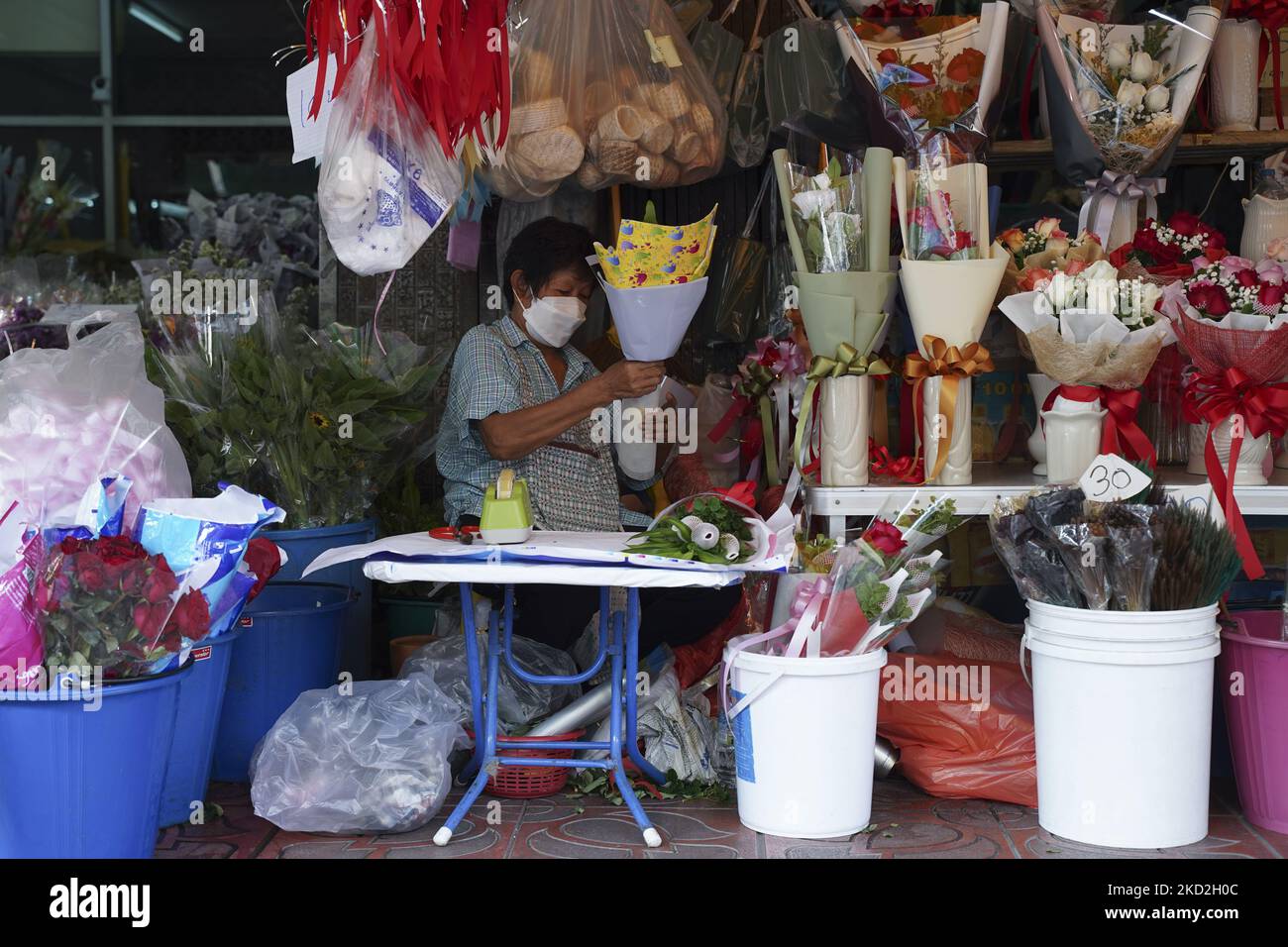 Un fornitore indossare maschere di protezione del viso preparare le rose per la vendita prima di San Valentino al mercato dei fiori Pak Klong Talad a Bangkok, Thailandia il 13 febbraio 2022. (Foto di Anusak Laowilas/NurPhoto) Foto Stock