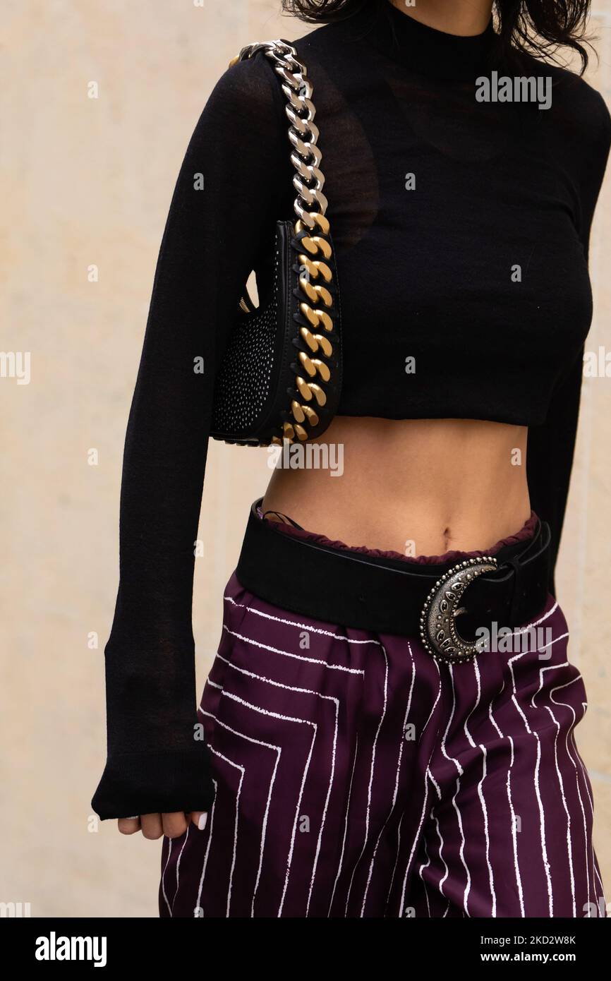 Parigi, Francia - Ottobre, 3, 2022: Donna indossa maniche lunghe a collo alto nere, bordo corto, cintura in pelle, borgogna con pantaloni a righe bianche, catena d'oro Foto Stock
