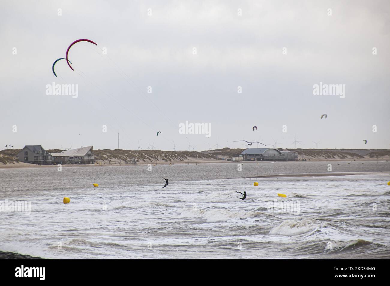 La gente fa kitesurf sulle onde e altri sport acquatici come tempesta Eunice colpisce con forti venti la riva olandese. Storm Eunice ha colpito i Paesi Bassi dopo la tempesta Dudley con una velocità di raffica di vento superiore a 120km km/h, con conseguenti danni a edifici, automobili e uccisioni di persone a causa della caduta di alberi. Il governo ha emesso un avvertimento rosso e 112 notifiche di emergenza allarme sui telefoni prima della tempesta hit.The Brouwersdam è una diga lunga sei chilometri che collega le province di Sud Olanda e Zeeland. Fa parte dei Delta Works ed è stata aperta al pubblico nel 1971. Brouwersdam, Ouddorp, Paesi Bassi Foto Stock