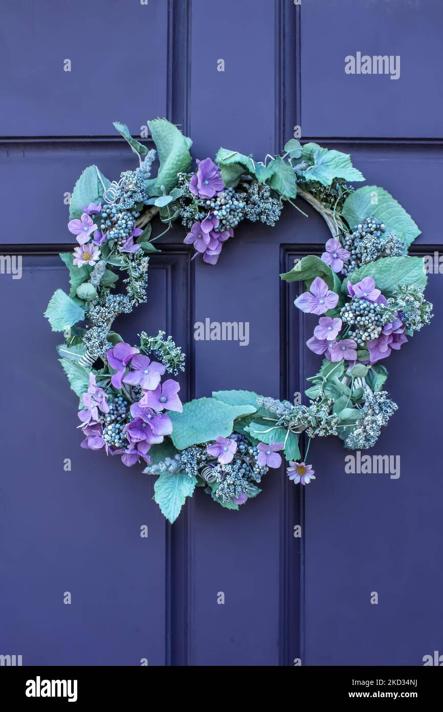 Primo piano di una bellissima corona verde e viola su una porta in legno viola profondo Foto Stock