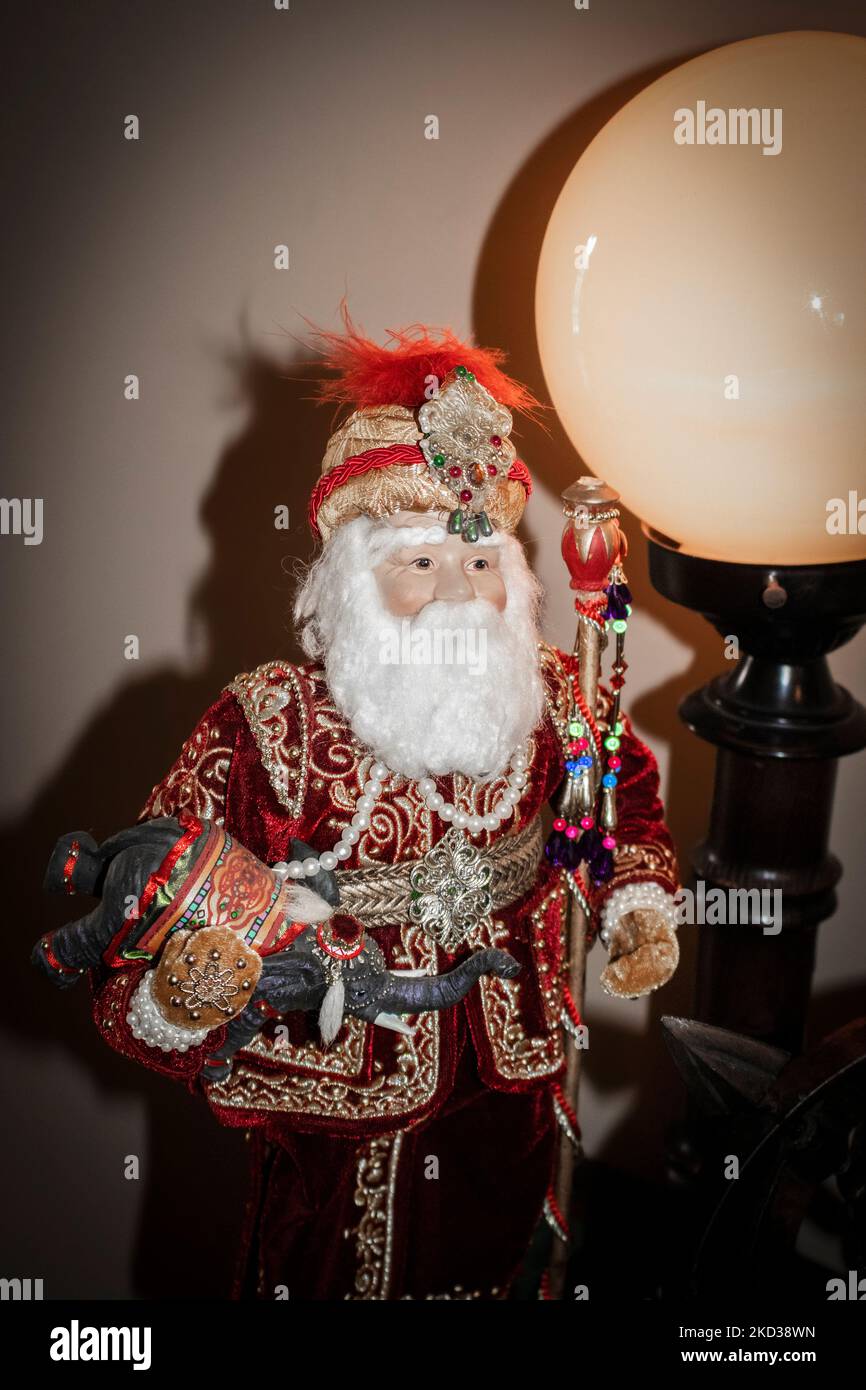 Figura di Santa indiana orientale che tiene piccolo elefante con la testa e bastone gioiellato in piedi da grande lampada del globo retrò - decorazione di Natale Foto Stock