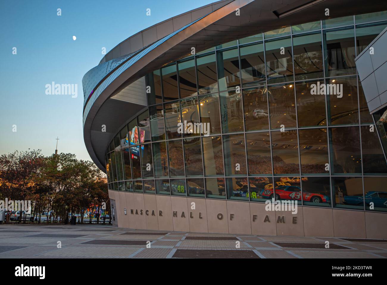 Vista esterna della NASCAR Hall of Fame a Charlotte, North Carolina, al crepuscolo con la luna sopra. Foto Stock