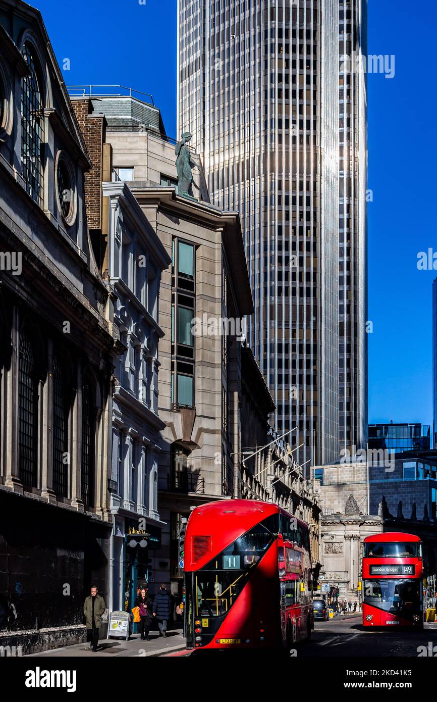 Due autobus di linea Red London si passano l'uno accanto all'altro con il gigantesco e iconico edificio NWB che torreggia sulla scena. La luce diurna illumina l'edificio Foto Stock