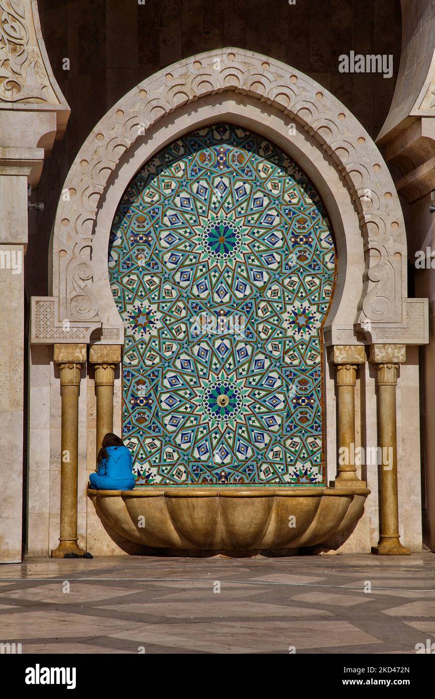 Ragazza seduta ai margini della fontana lungo il cortile della Moschea Hassan II nella città di Casablanca, Marocco, Africa. La Moschea di Hassan II è la più grande moschea del Marocco e la 7th più grande al mondo. Il suo minareto è il più alto al mondo, con i suoi 210 metri (689 piedi). (Foto di Creative Touch Imaging Ltd./NurPhoto) Foto Stock