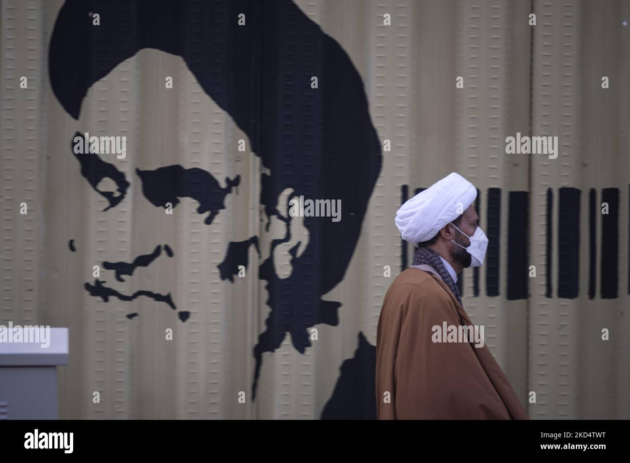 Un chierico iraniano passa davanti a un graffito di Ayatollah Ruhollah Khomeini, fondatore e primo leader spirituale della Repubblica islamica dell'Iran, nella città Santa di Qom 145km (90 miglia) a sud di Teheran il 10 marzo 2022. (Foto di Morteza Nikoubazl/NurPhoto) Foto Stock