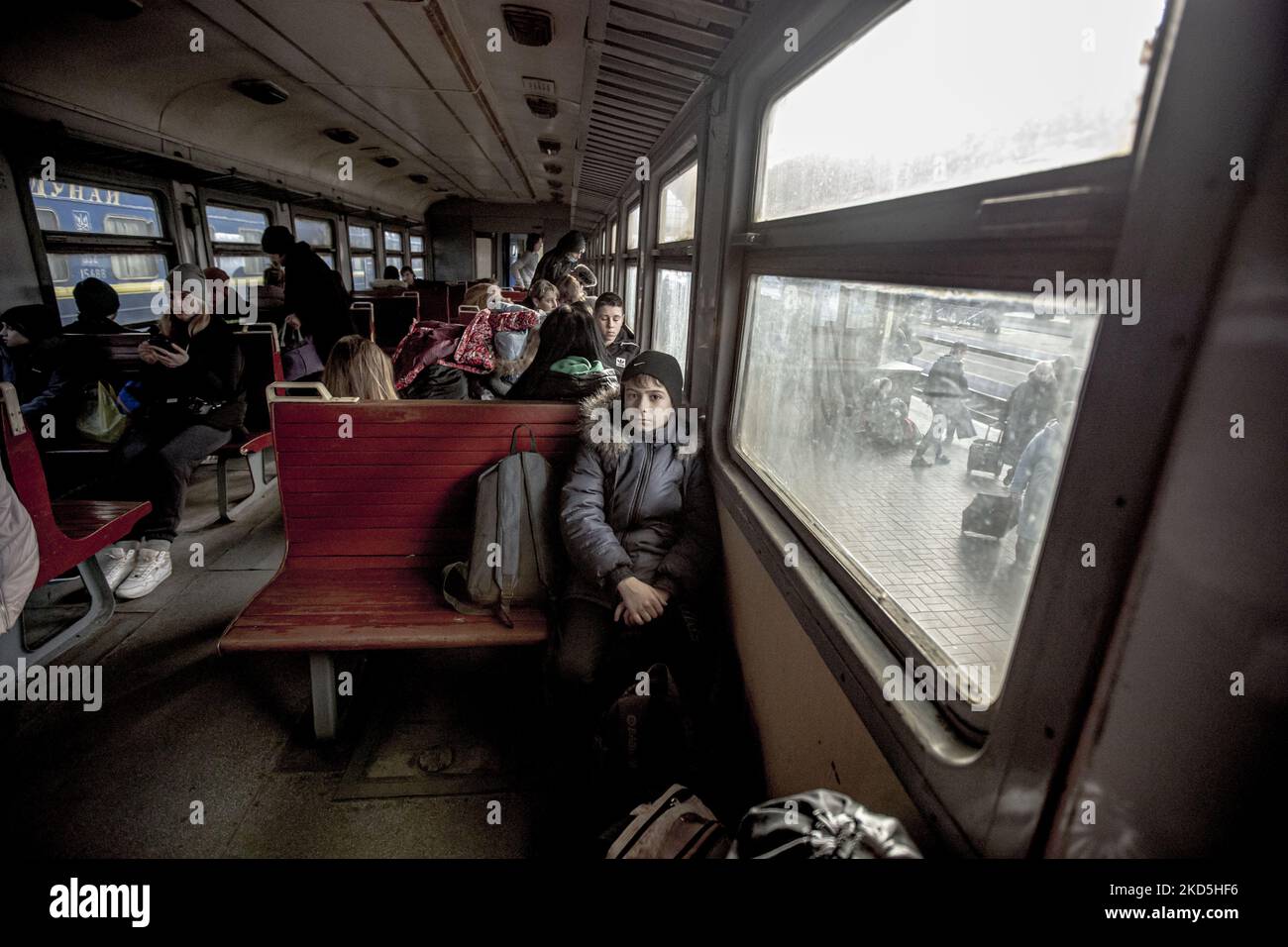 Un ragazzo seduto da solo in treno. La gente Ucraina in una vecchia macchina ferroviaria arrivare velocemente dopo l'attesa metropolitana a Lviv stazione ferroviaria passaggio il treno per arrivare e salire a bordo delle carrozze perché la stazione è considerata come un obiettivo militare. Il treno attraverserà le frontiere ucraine polacche e si sposterà ulteriormente verso la Polonia e altri paesi europei. Il 15 marzo le sirene per RAID aereo suonavano due volte, una al mattino e una alla sera. Secondo le Nazioni Unite - UNHCR più di 3,3 milioni di rifugiati hanno lasciato il paese come annunciato dalle Nazioni Unite e hanno mostrato i dati su una mappa mentre a. Foto Stock