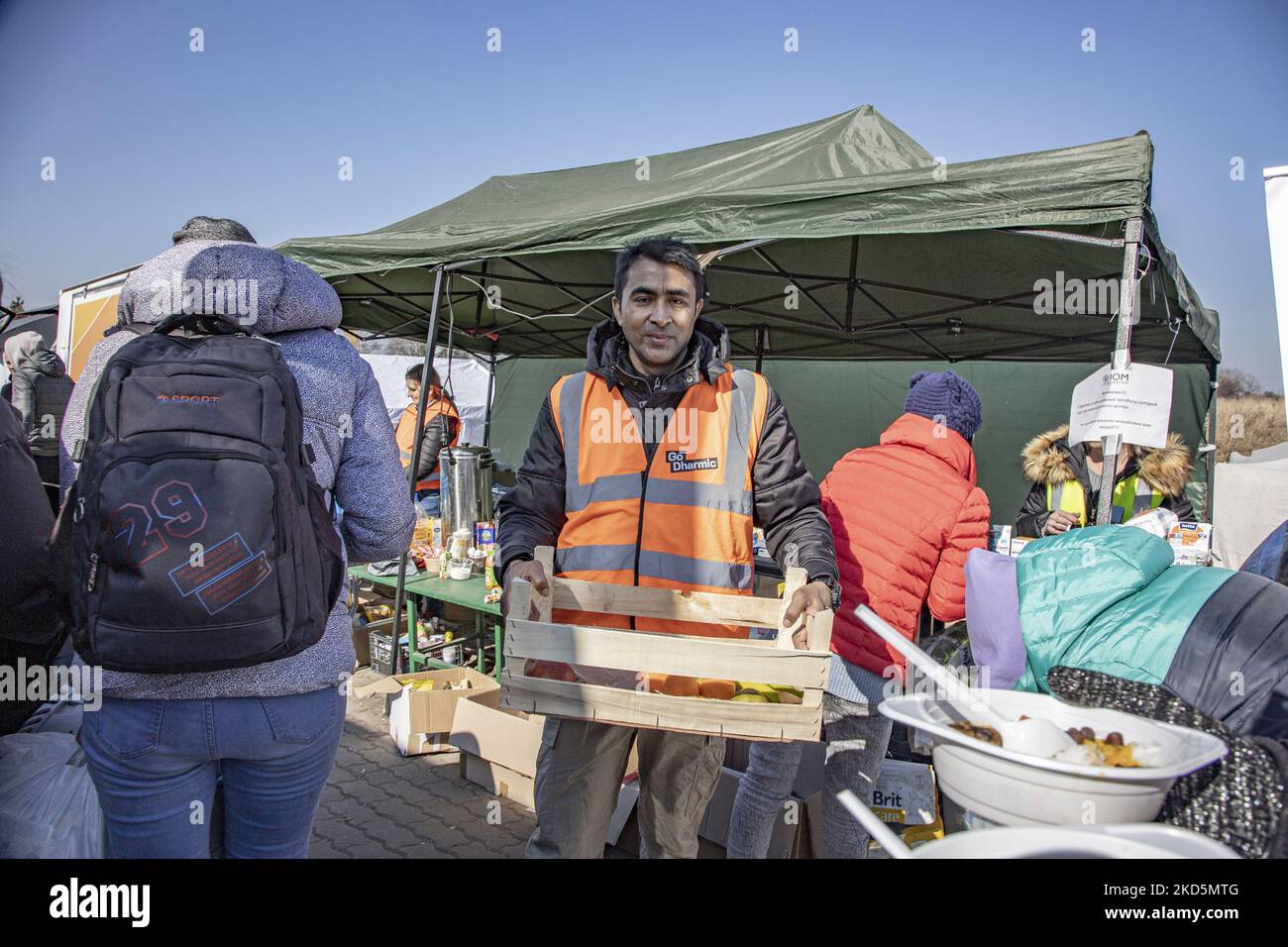 Un volontario offre cibo e frutti ai rifugiati in arrivo. I rifugiati civili arrivano continuamente dall'Ucraina al valico di frontiera di Medyka Shehyni in Polonia. Dopo aver superato il controllo di frontiera, gli ucraini passano attraverso le tende con le ONG, i volontari e altre organizzazioni di beneficenza che forniscono aiuti umanitari, cibo, vestiti, assistenza medica e poi si imbarcheranno sugli autobus appositamente assegnati per trasferirli ai centri di registrazione o trasferirli in altre città della Polonia come Przmesyl, Cracovia o più in Europa. Secondo le Nazioni Unite - UNHCR più di 3,3 milioni di rifugiati hanno lasciato il paese come N unita Foto Stock