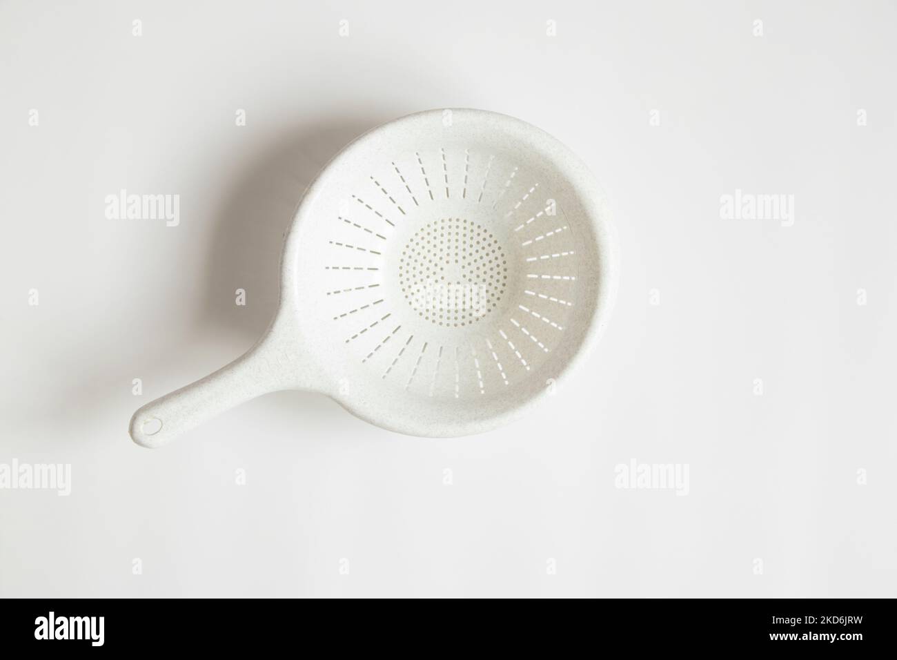 La plastica bianca del colander si trova su un primo piano bianco dello sfondo Foto Stock