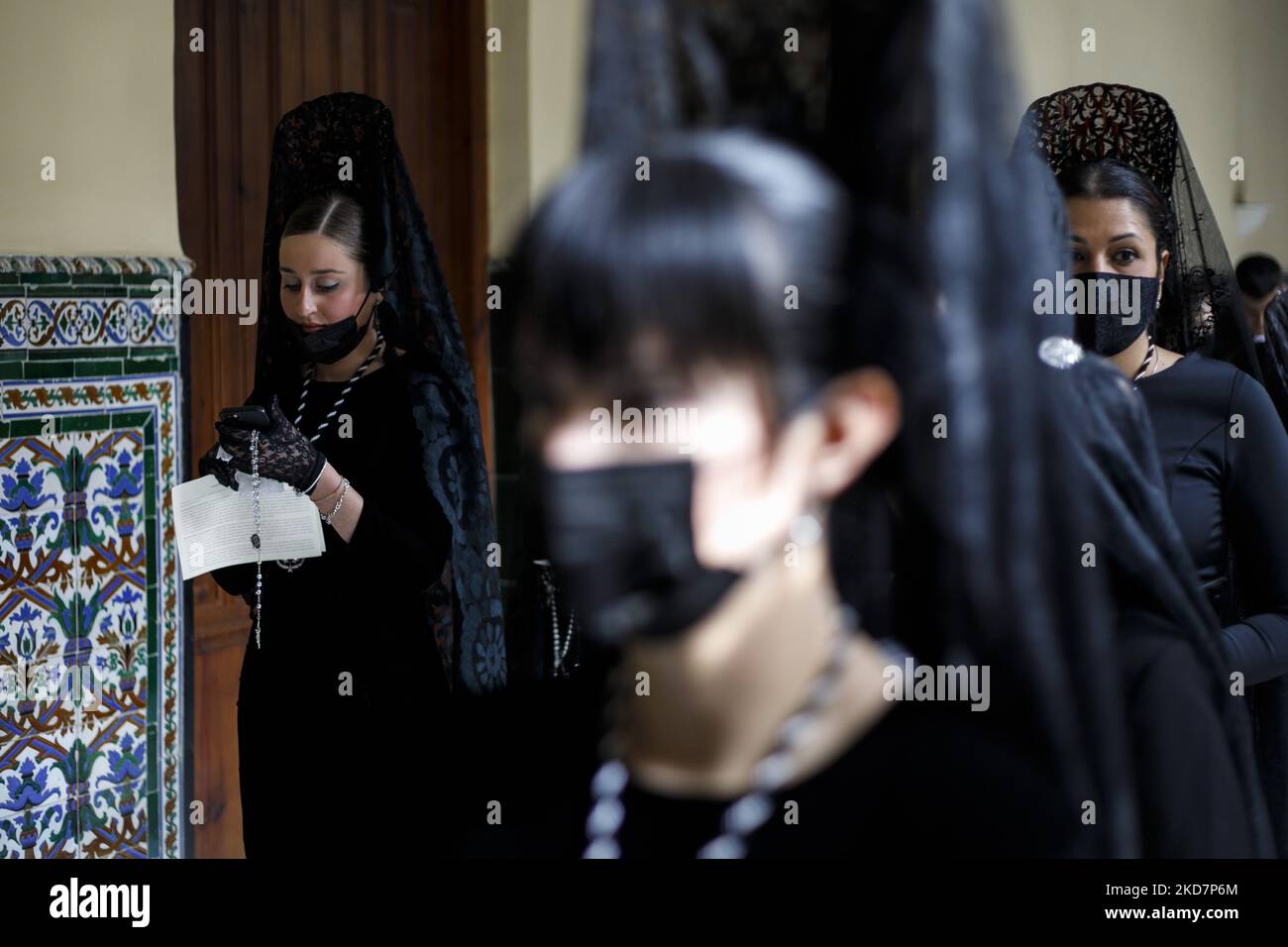 Un penitente vestito di nero dalla Confraternita Escolapios guarda il suo cellulare durante il Venerdì Santo a Granada, Spagna, il 15 aprile 2022. La settimana Santa torna in Spagna con le tradizionali processioni nelle strade dopo due anni di interruzione a causa della pandemia di coronavirus. (Foto di Ãlex CÃ¡mara/NurPhoto) Foto Stock
