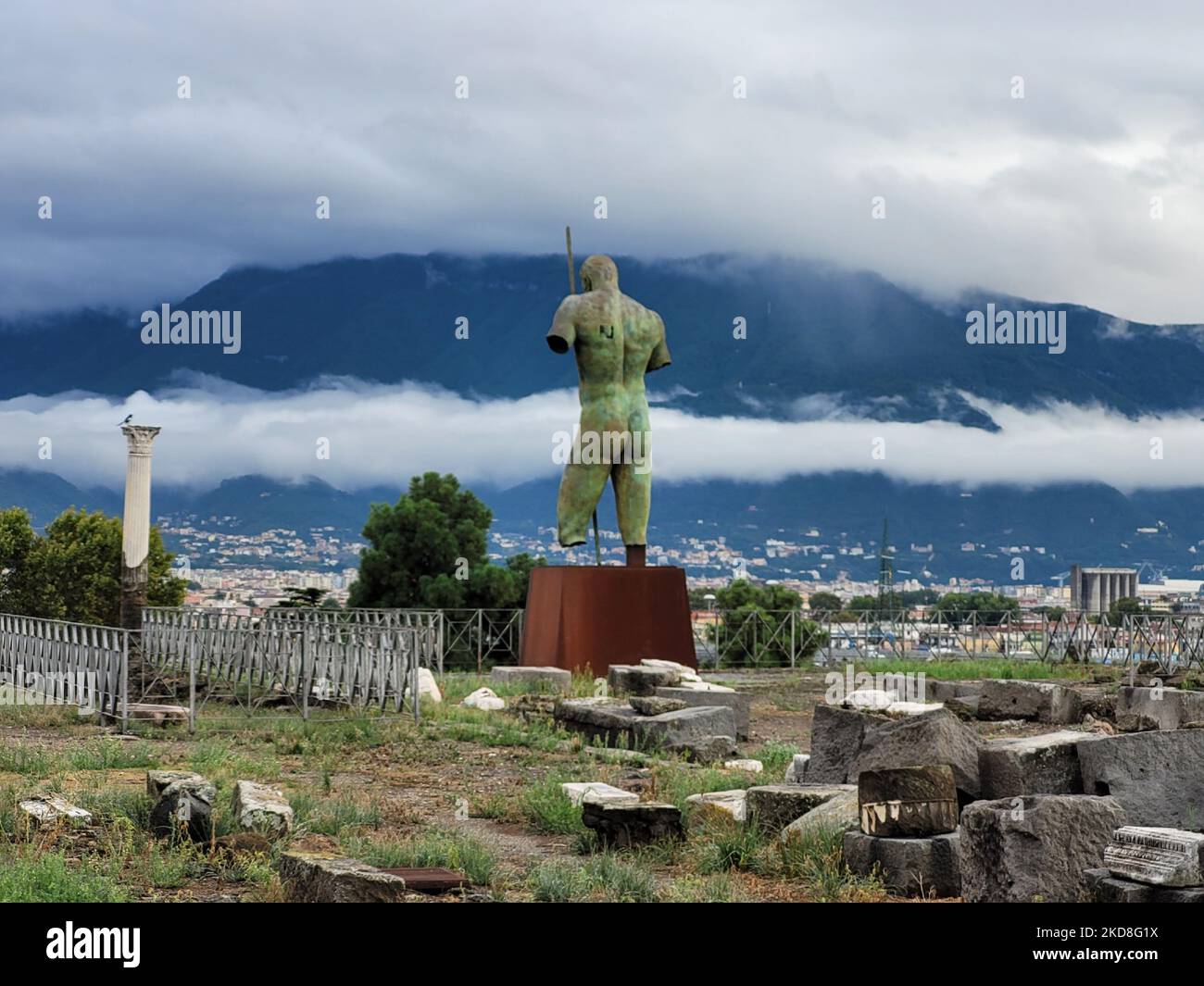 Statua di un uomo semidistrutto nelle rovine di Pompei, Italia con le montagne sullo sfondo Foto Stock