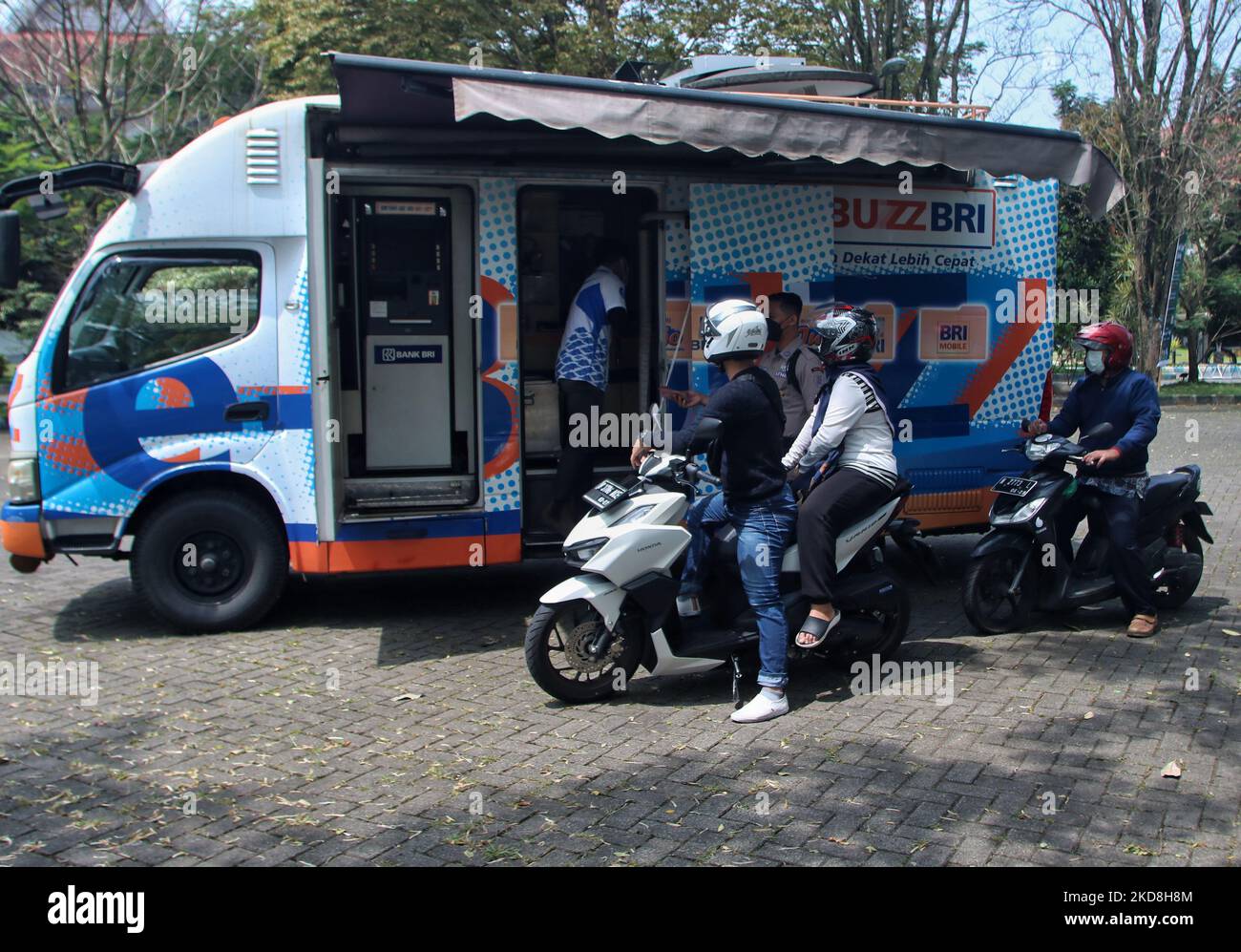 Un funzionario della Banca serve i residenti che stanno facendo la coda per scambiare denaro con nuovi piccoli tagli da Drive Thru presso un servizio mobile di cassa a Malang, Giava Orientale, Indonesia, il 26 aprile 2022. Lo scambio di tagli di rupiah è inteso come premio in denaro (un simbolo di amore e di successo) per i membri della famiglia durante la celebrazione di Eid al-Fitr. La banca centrale ha preparato piccole denominazioni di denaro per le esigenze della comunità in occasione della celebrazione di Eid al-Fitr 1443 tanto quanto Rp. 175,26 trilioni di dollari con un limite di Rp. 3,8 milioni di dollari al giorno. (Foto di Aman Rochman/NurPhoto) Foto Stock