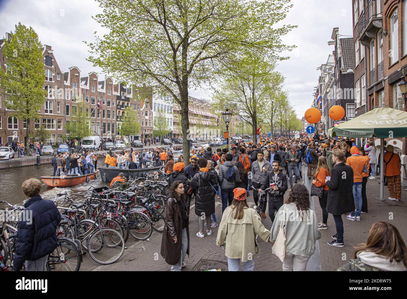 I Paesi Bassi festeggiano il King's Day dopo due anni di cancellazione a causa della pandemia di Coronavirus COVID-19 e delle restrizioni e misure di blocco. Migliaia di abitanti del luogo, festeggiatori e visitatori hanno visitato il centro della città, i parchi vicino al Rijksmuseum, i canali di Amsterdam per celebrare con varie feste il compleanno del re Willem-Alexander conosciuto come Koningsdag, una festa nazionale olandese. Tutti i tipi di barche e navi sono visti nei canali che passano sotto i famosi ponti e vicino alle case strette di Amsterdam con persone che ballano e divertirsi. Le barche sfilano giù nel dentro Foto Stock