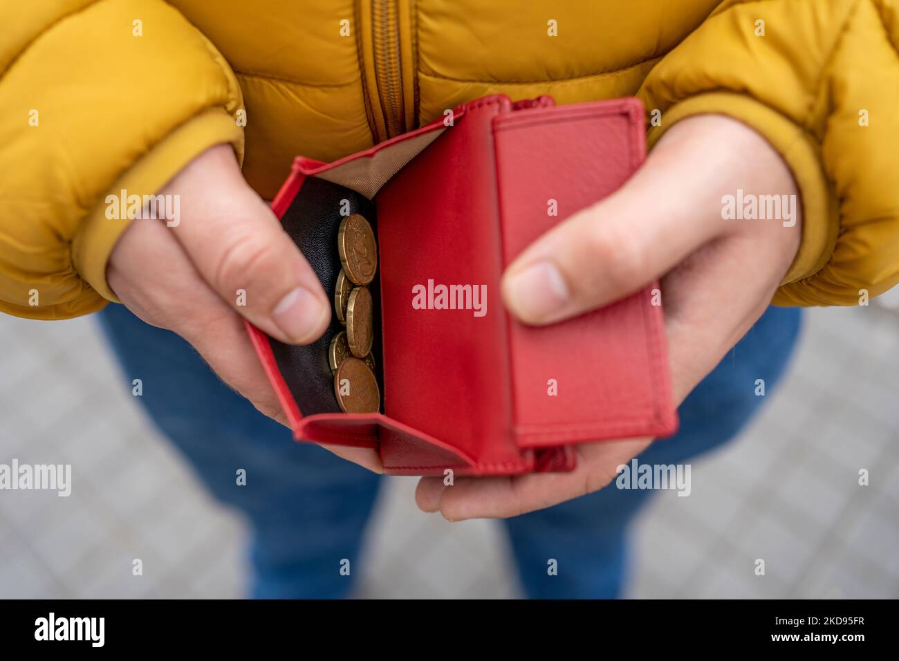 primo piano della mano di un uomo che tiene un portafoglio e che mostra le monete in euro in esso contenute. Foto Stock