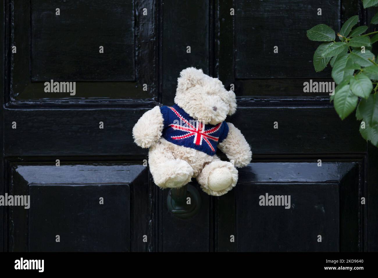 Orsacchiotto con jumper bandiera di Unione sull'esterno di una porta di fronte nera ad una casa in Inghilterra, Regno Unito Foto Stock