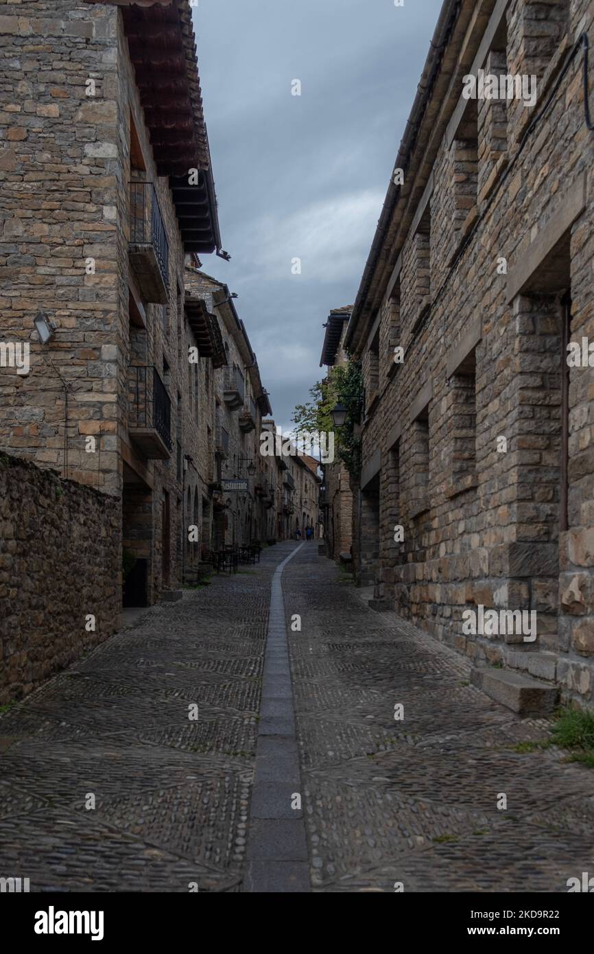 Uno stretto vicolo tra edifici medievali nel comune di Ainsa-Sobrarbe a Huesca, Aragona, Spagna. Scatto verticale Foto Stock