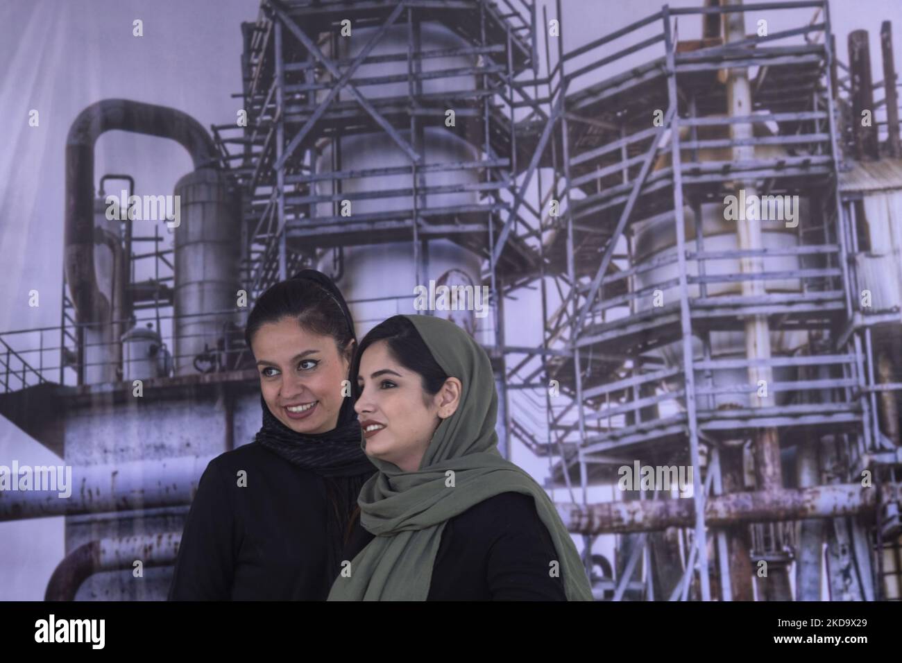 Due anni dopo l'epidemia di COVID-19 in Iran, le donne iraniane sorridono mentre si trovano di fronte a un'immagine degli impianti petroliferi alla 26th° esposizione internazionale del petrolio, del gas, della raffinazione e della petrolchimica a Teheran il 13 maggio 2022. (Foto di Morteza Nikoubazl/NurPhoto) Foto Stock